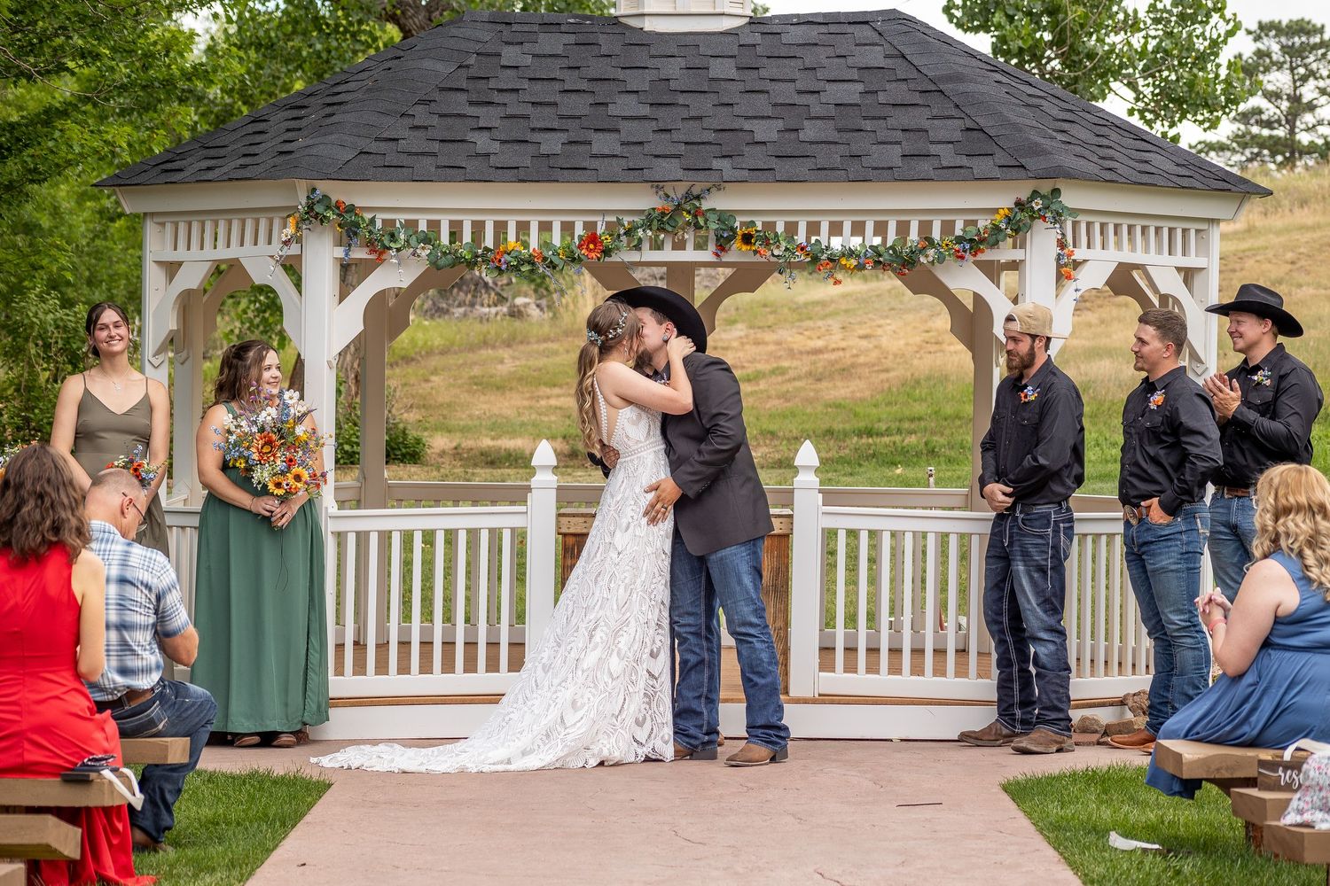 Wedding guests gather on a patio during an outdoor summer celebration at a gazebo venue.