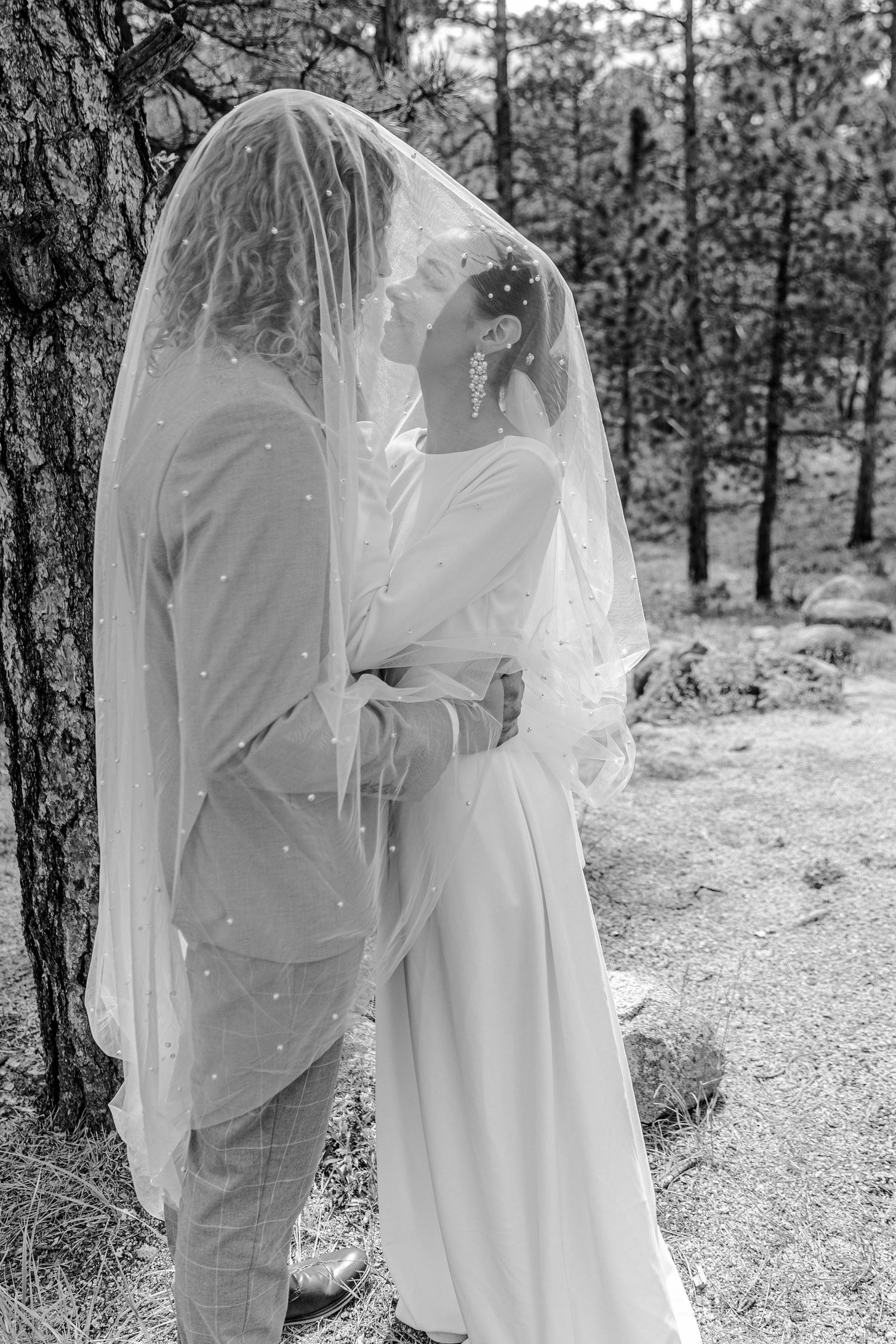 Black and white wedding photography capturing intimate moments between a couple in a forest setting.