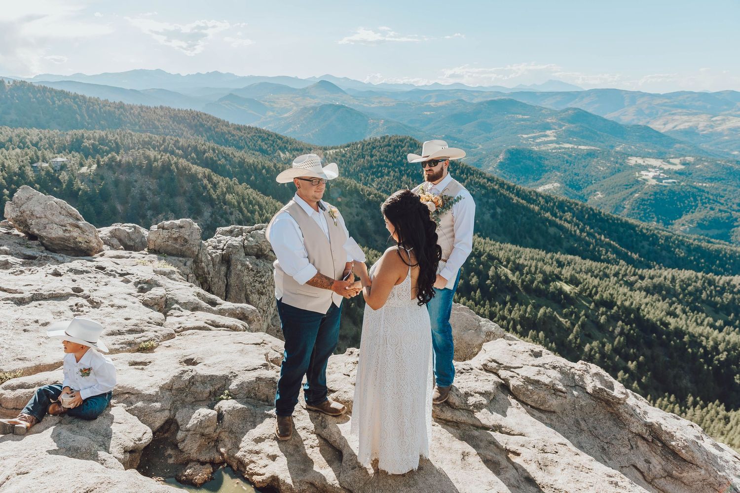 Wedding ceremony takes place on a dramatic rocky mountain overlook with sweeping valley views.