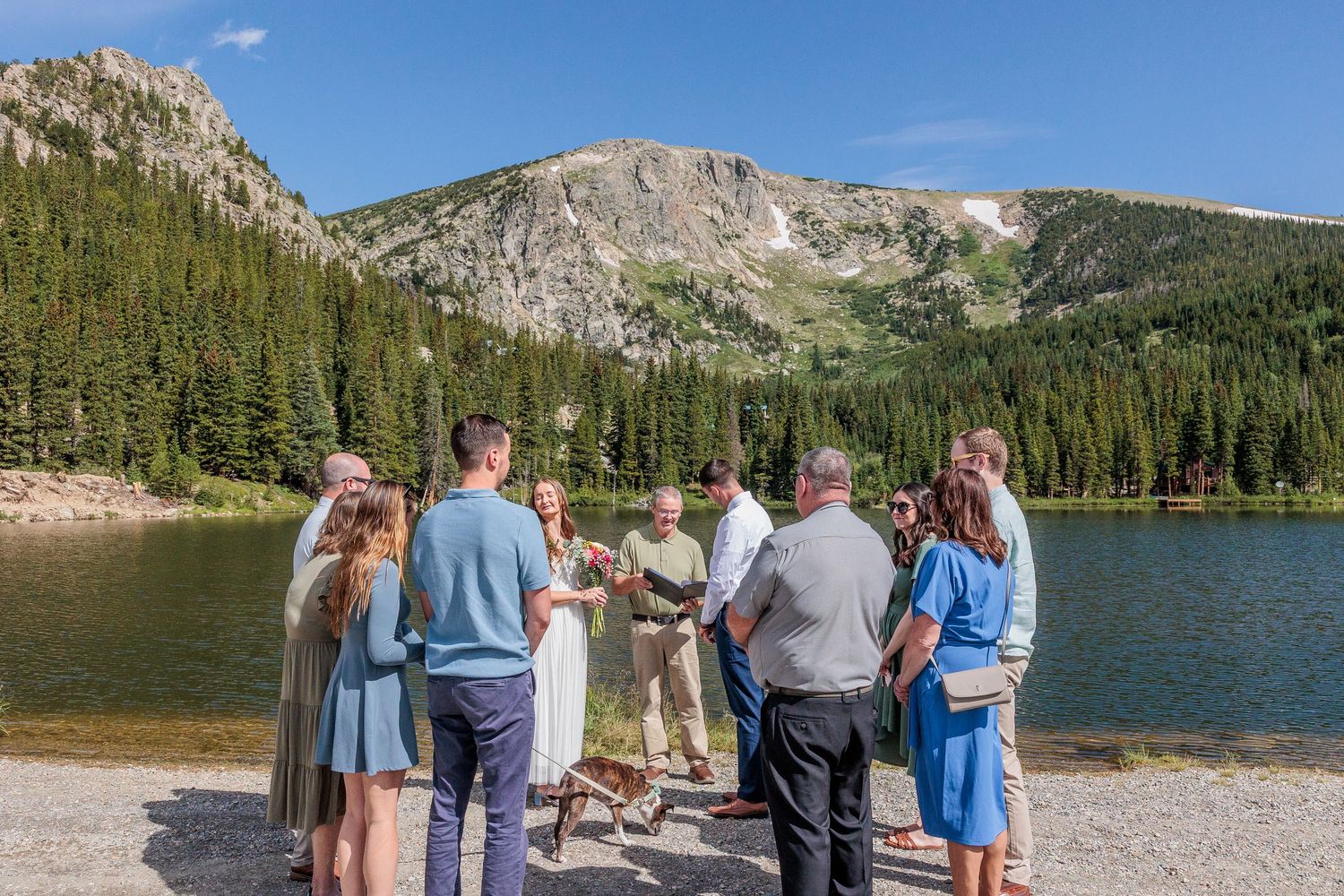 Group of hikers enjoying scenic mountain views along a lake shore trail in a rugged wilderness landscape.