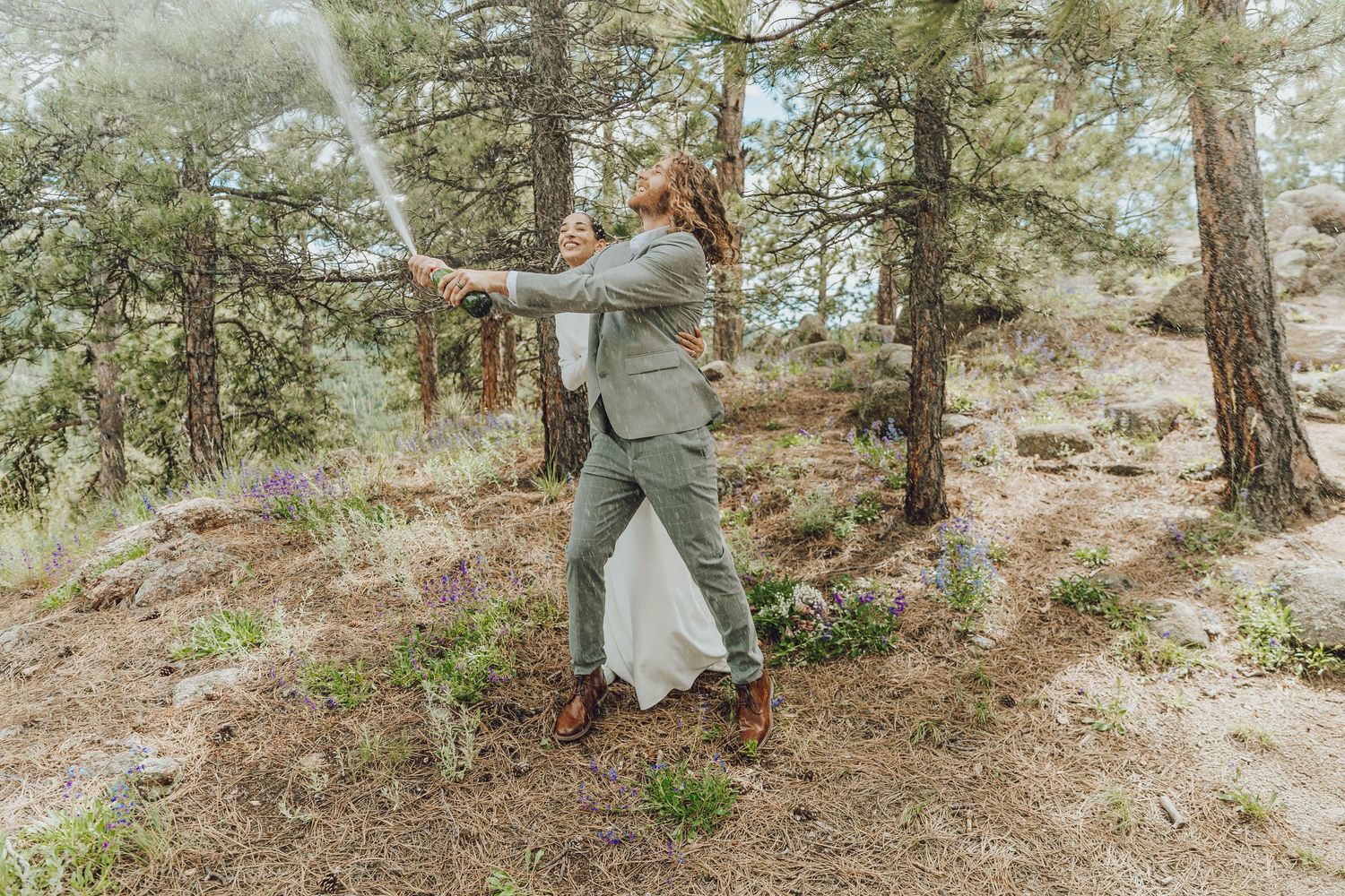 A couple poses together in a sunlit forest during their wedding day photoshoot.