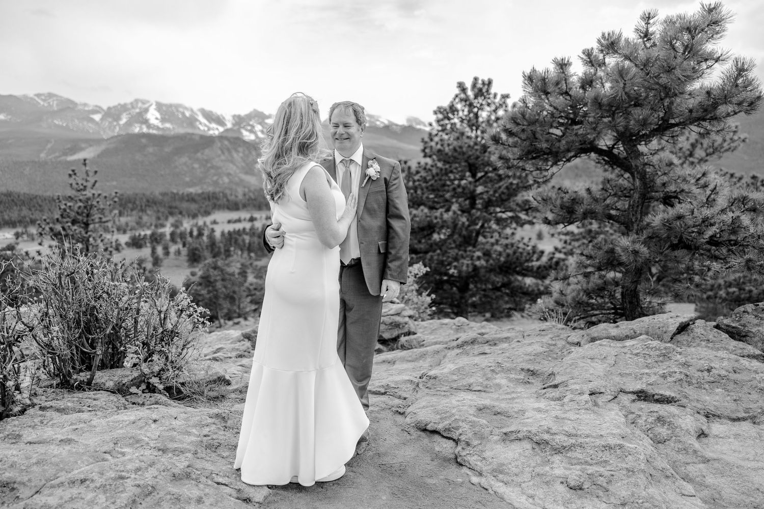 Scenic mountain wedding ceremony with snow-capped peaks and evergreen trees in the background.