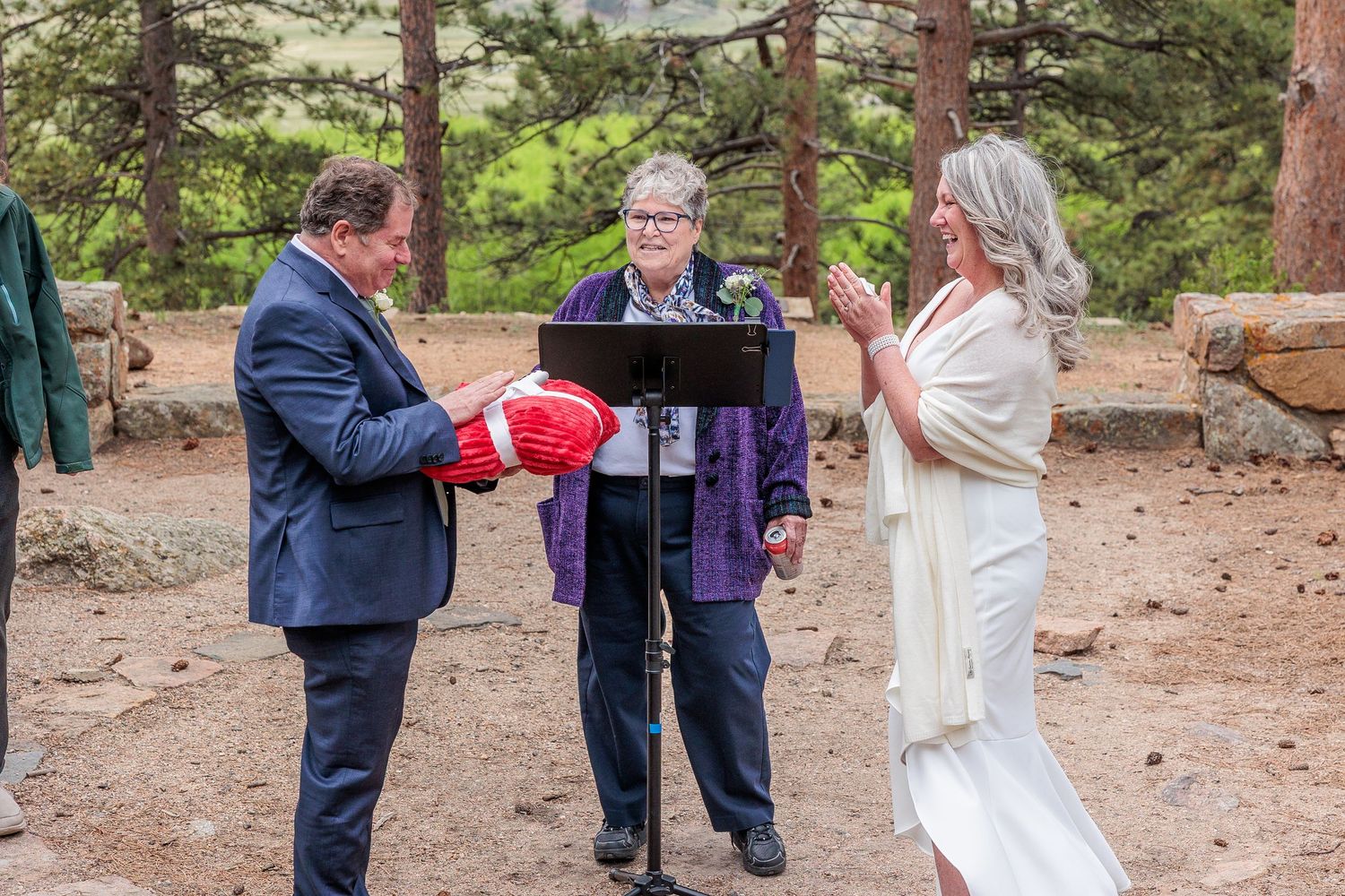 A group of people gather in a forest setting for an outdoor ceremony or celebration.