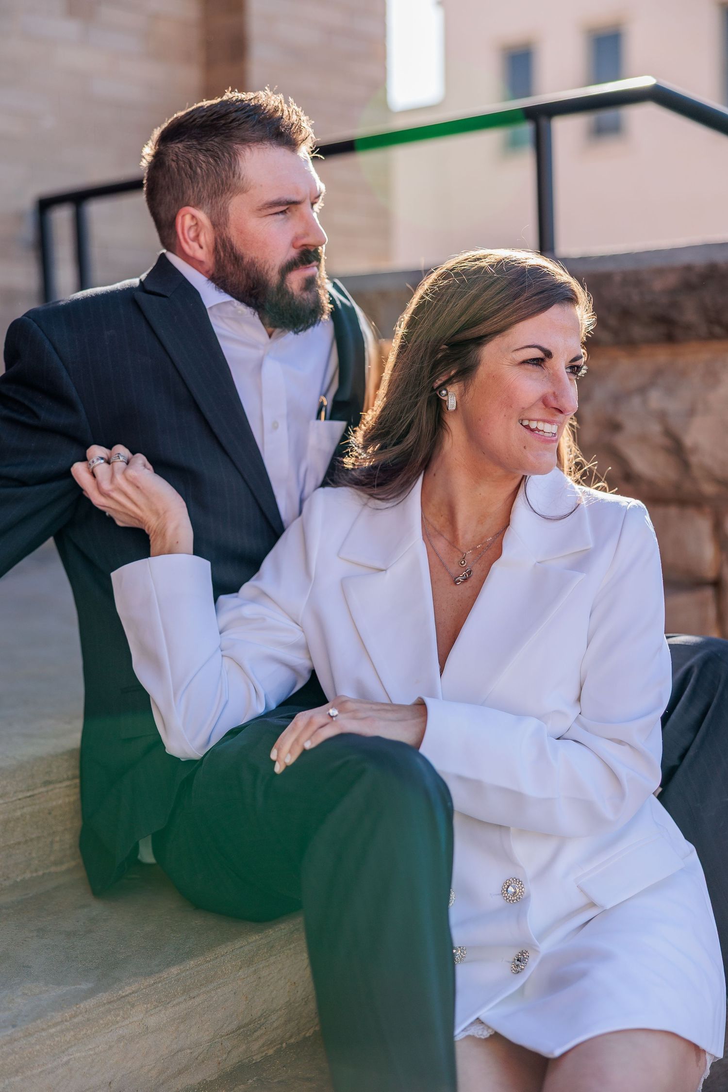 A playful moment shared on a wooden bench in casual formal attire.