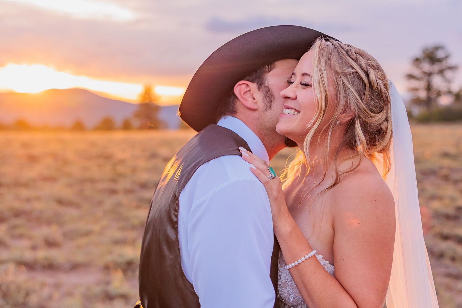 A romantic couple shares an intimate moment at sunset in a rustic outdoor setting with warm golden lighting.