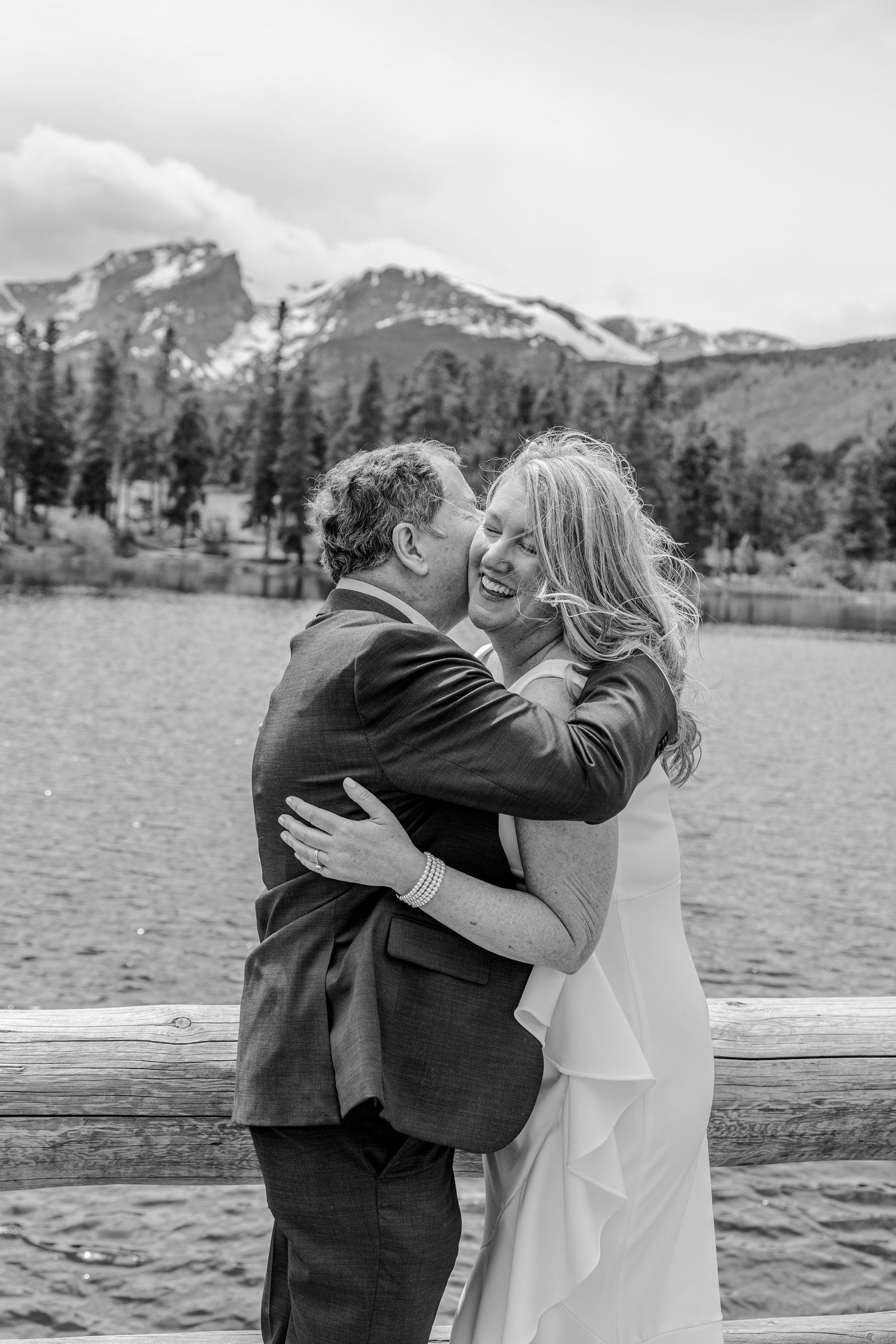 A romantic black and white moment shared between a couple by a mountain lake.