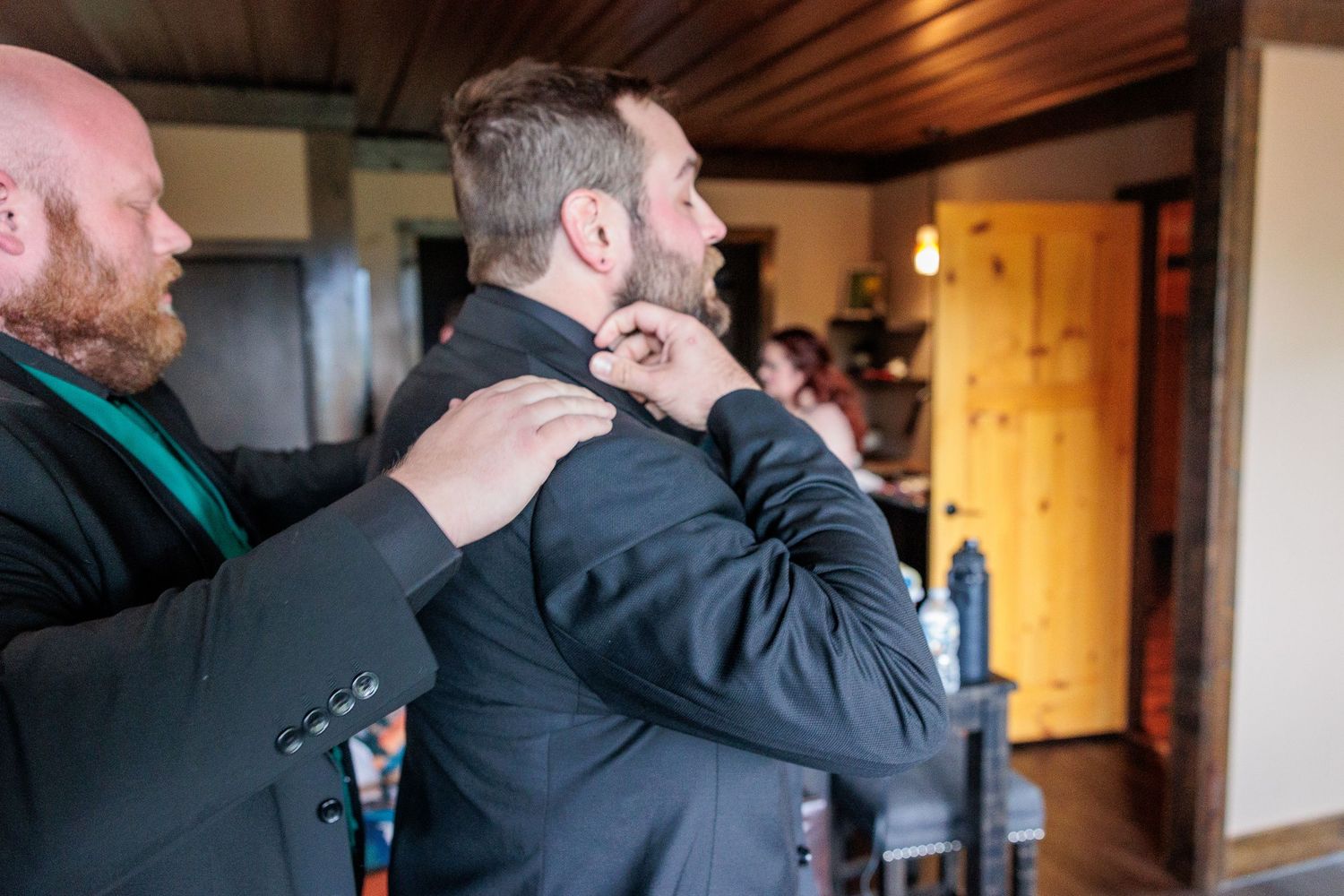 Two people share an emotional embrace in a warmly lit wooden interior space.