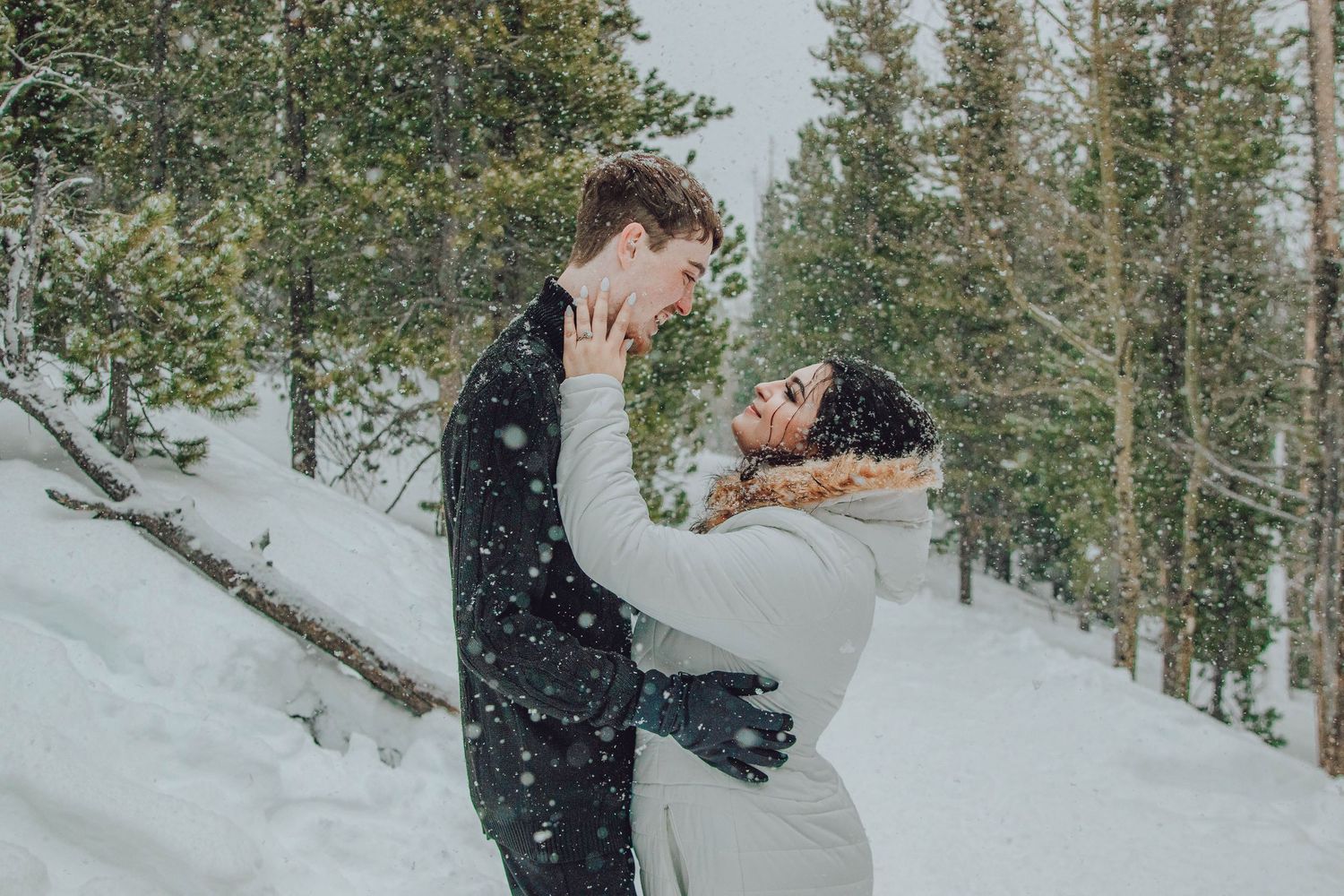 A snowy winter wedding photoshoot among evergreen trees in the mountains.