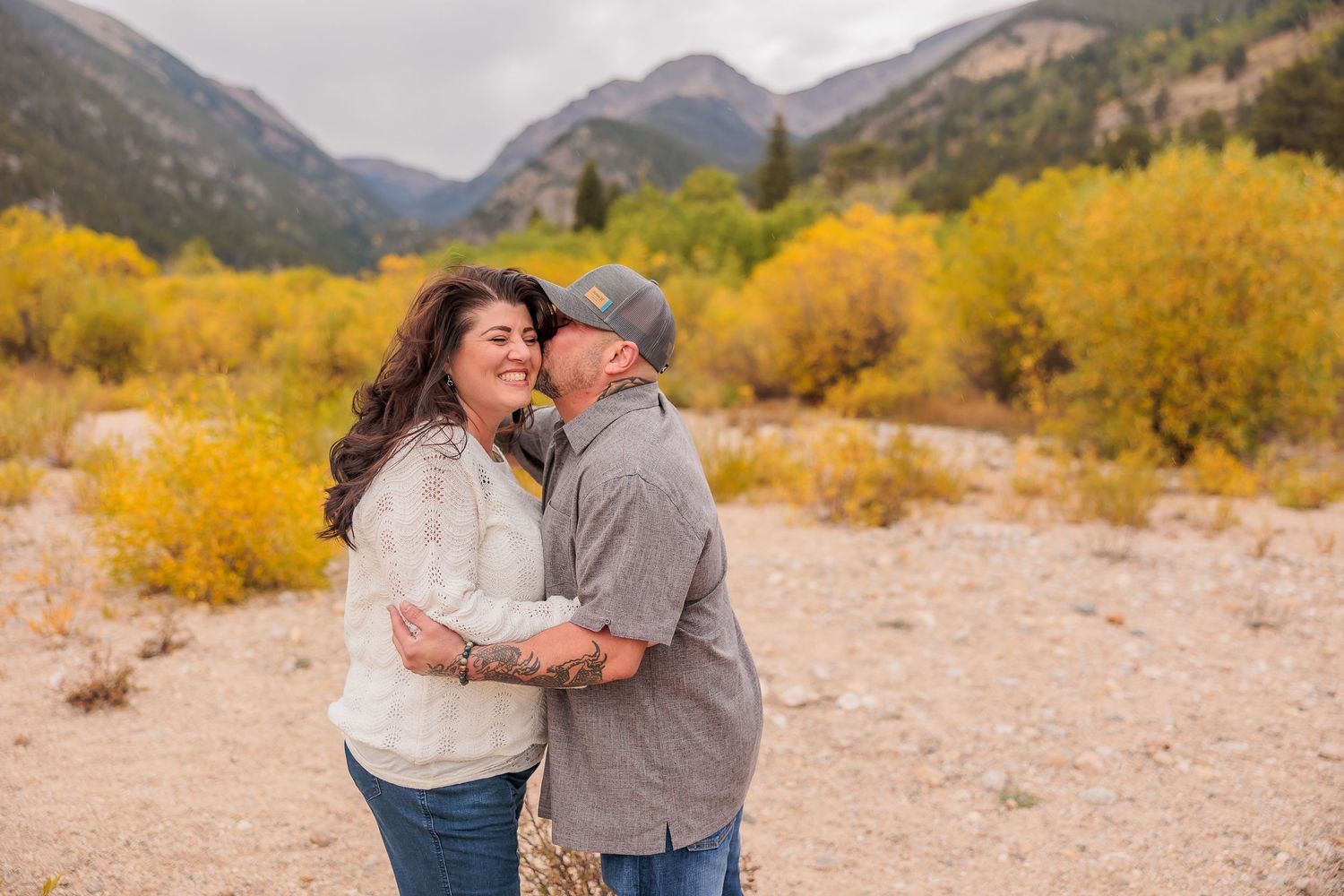 Mountain landscape with golden fall colors frames a romantic moment against rugged peaks.