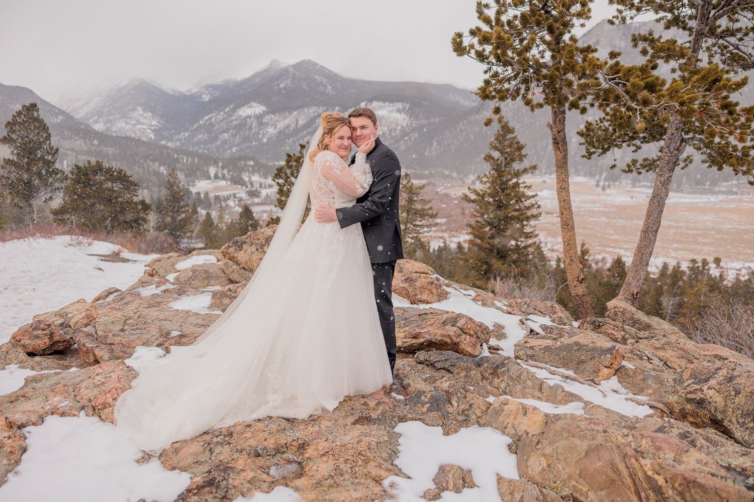 A couple shares an intimate moment during their winter mountain wedding photoshoot in a snowy Colorado landscape.