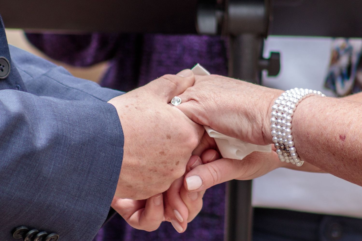 Close-up view of hands joining together in an intimate gesture against a dark background.