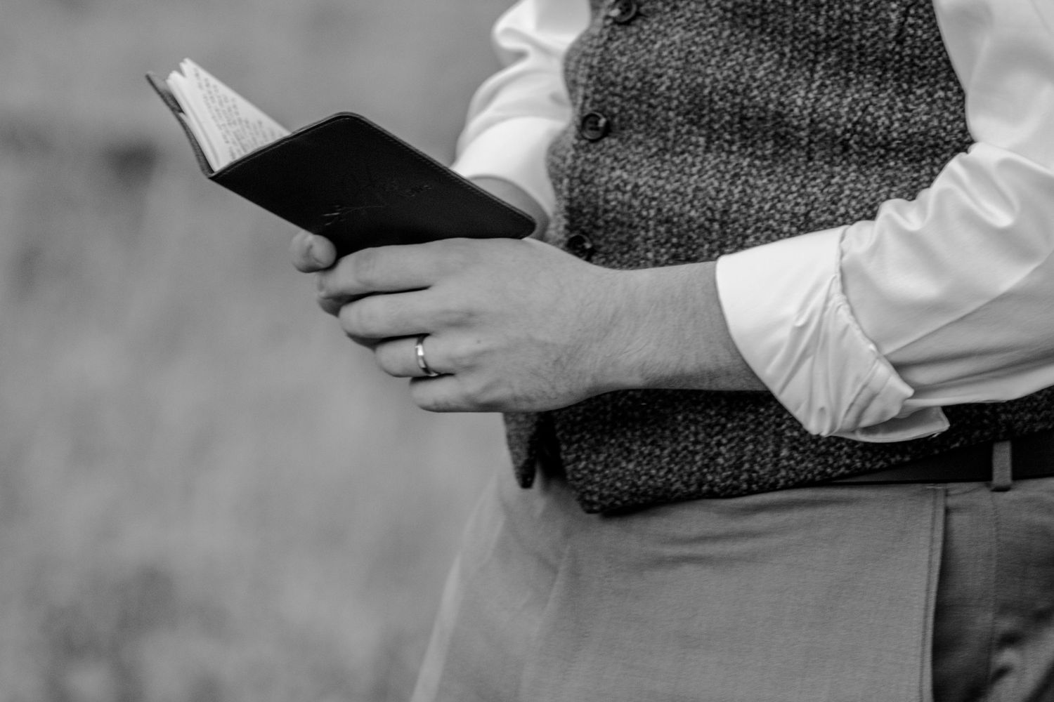 Professional in white shirt holds open book while reading in black and white photograph.
