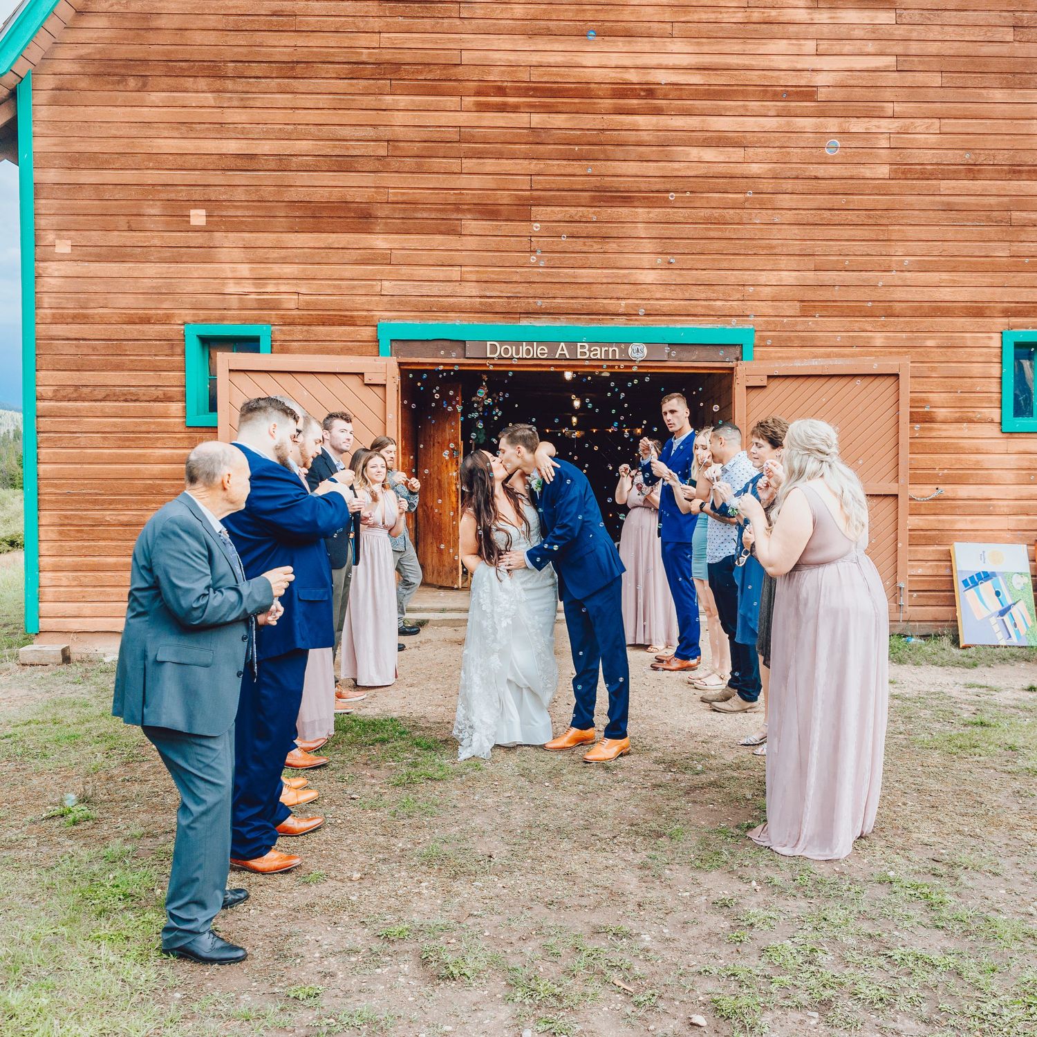 Wedding guests gather outside a wooden venue for a celebration.