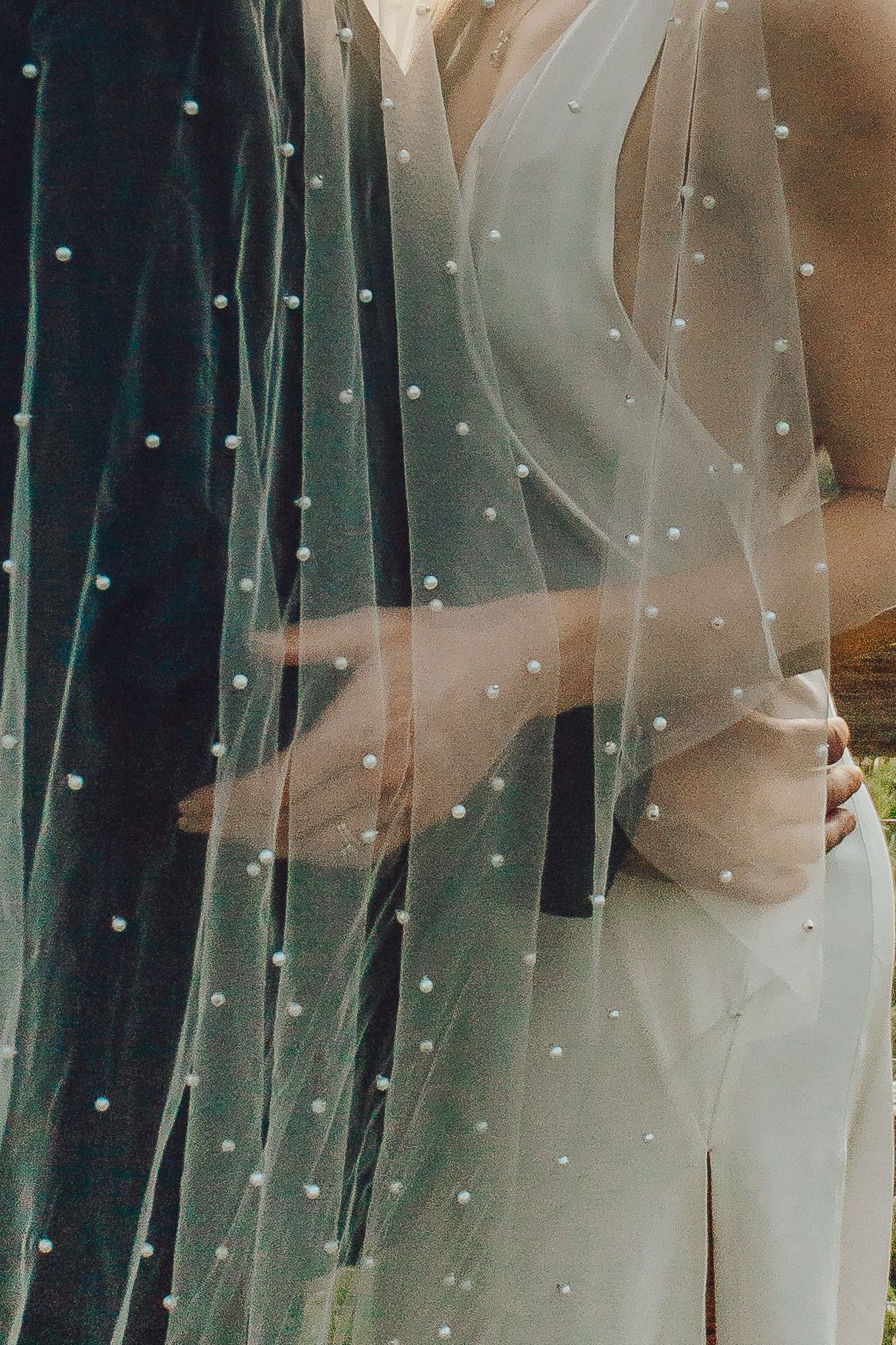 Close-up detail of a delicate pearl-dotted wedding veil in soft lighting.