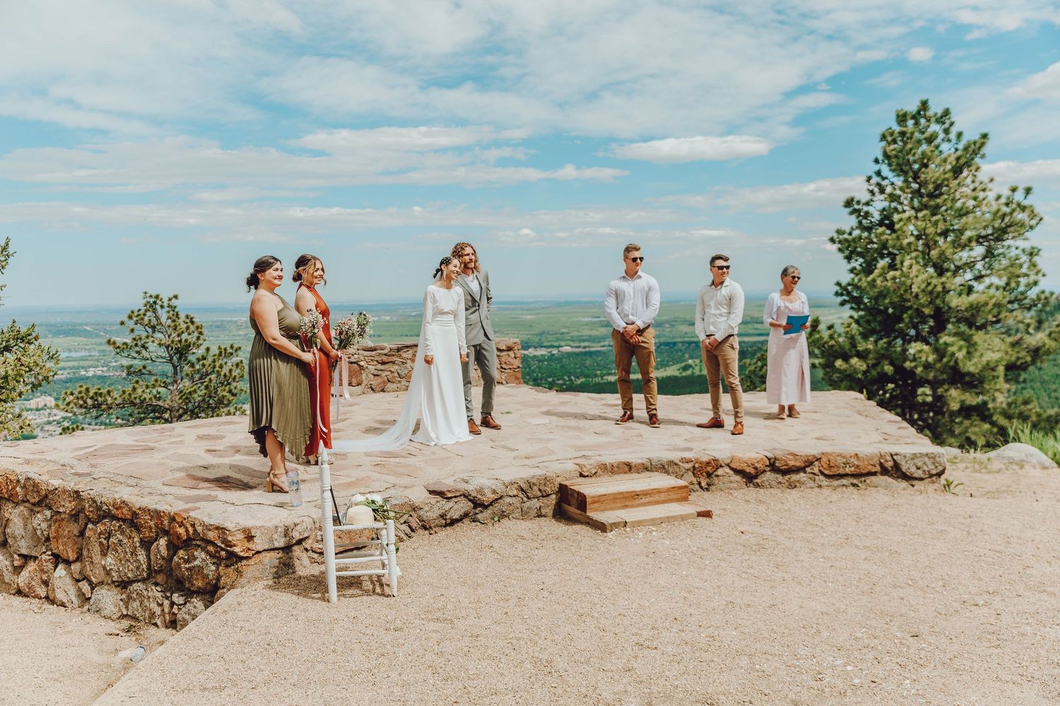 Panoramic view of a mountain wedding ceremony with guests gathered on a scenic rocky overlook.