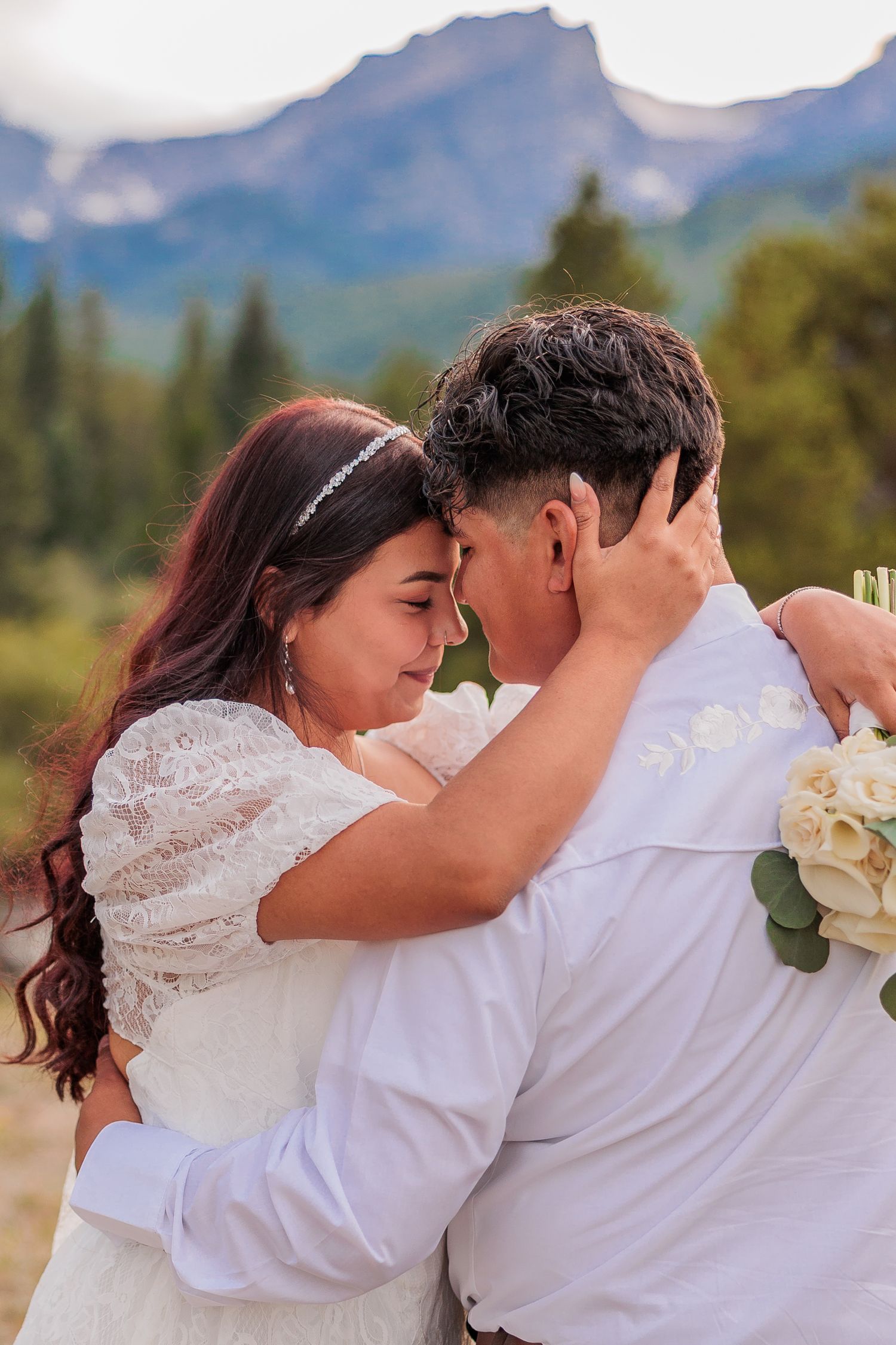 A romantic embrace captured against a stunning mountain backdrop during a wedding celebration.