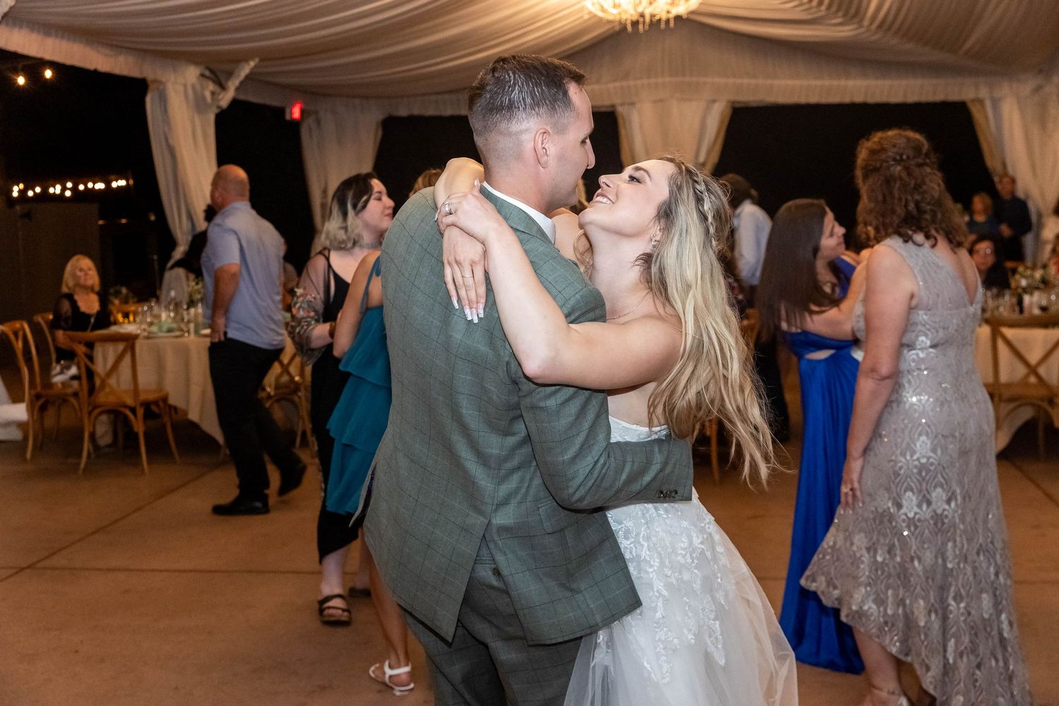 Wedding reception dance party under draped fabric ceiling with romantic lighting.