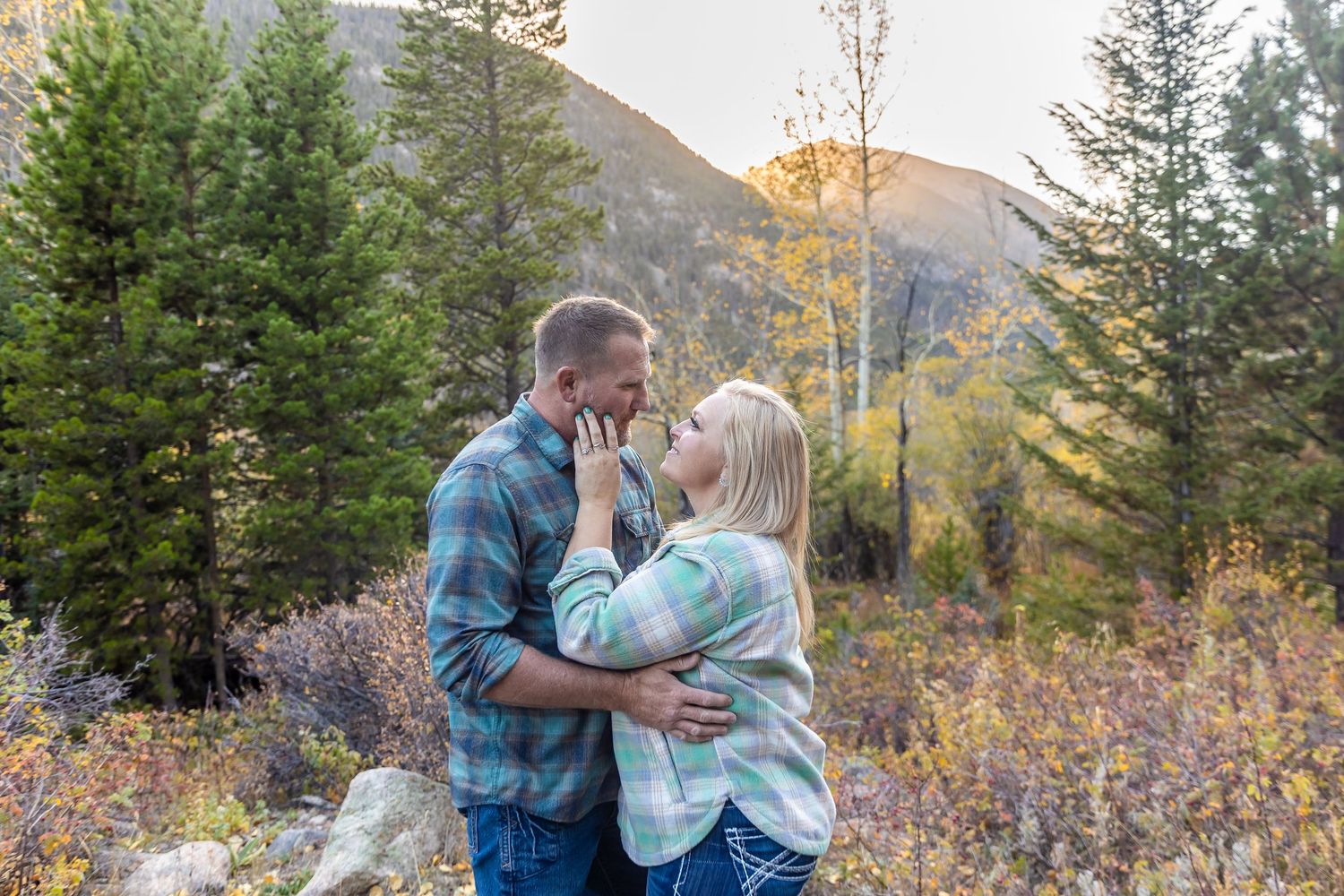 A romantic moment in nature surrounded by evergreen trees and autumn foliage in the mountains at sunset.