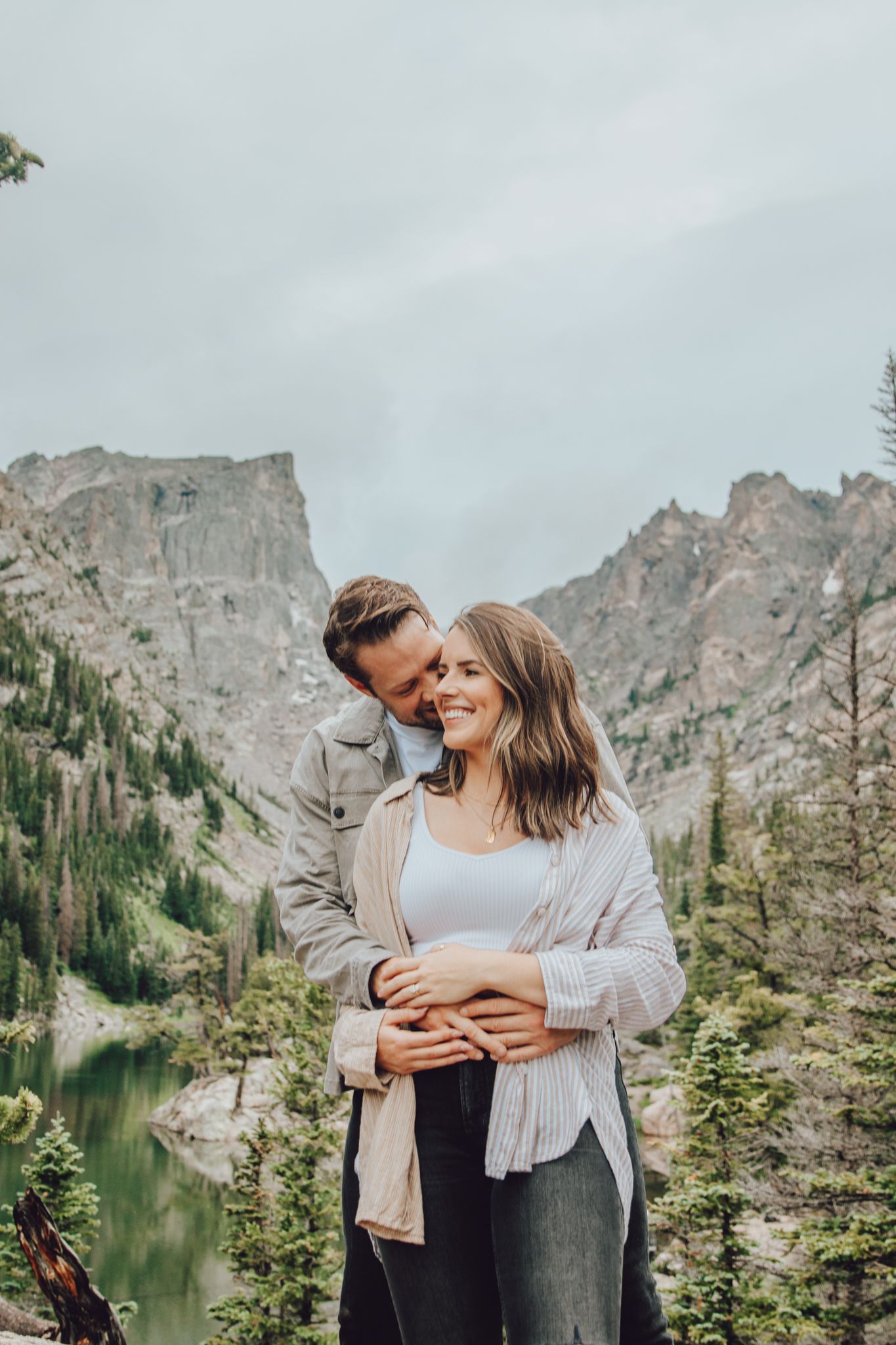 A romantic embrace by an alpine lake with dramatic mountain peaks in the background.
