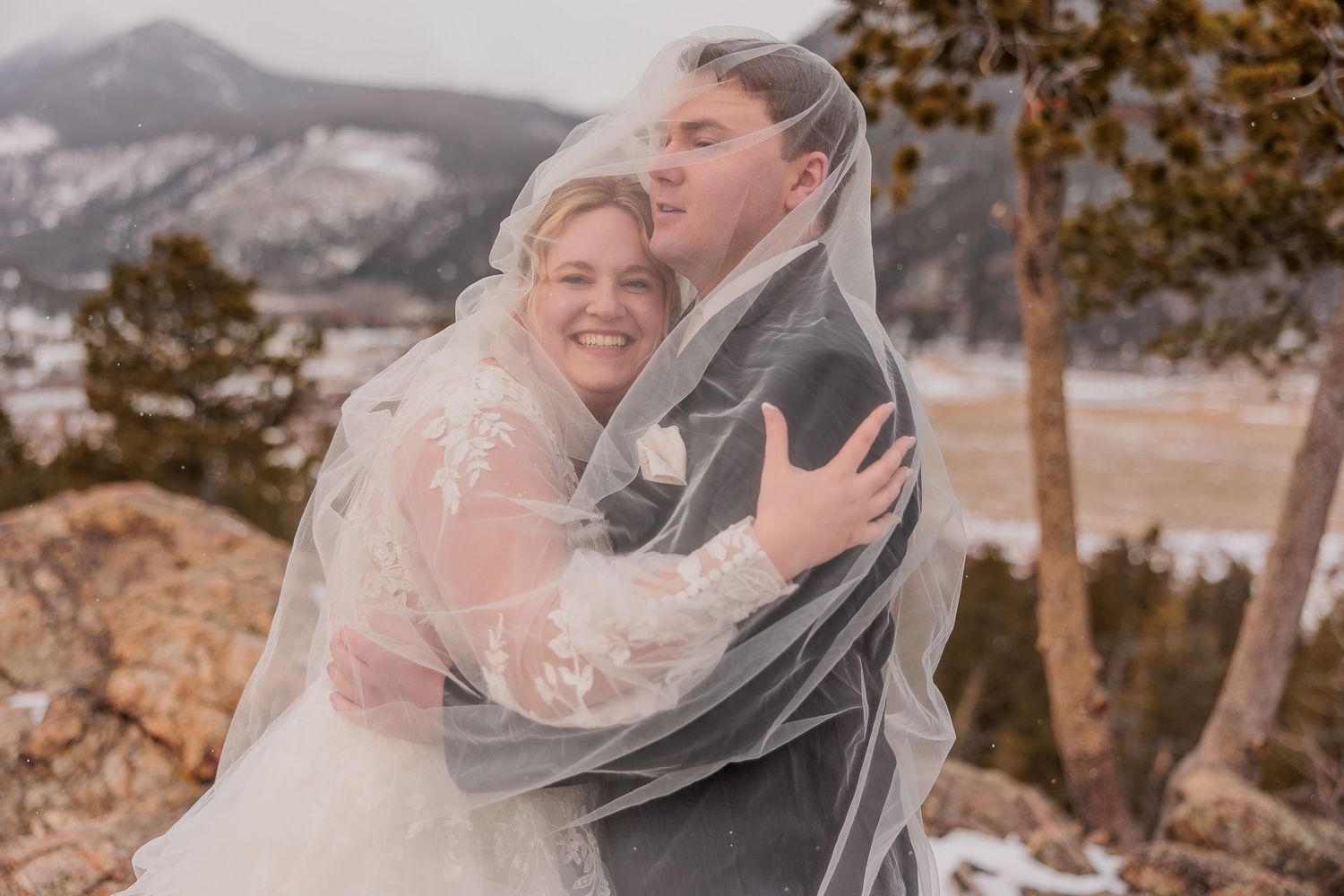 Romantic wedding couple shares intimate moments in the mountains with a flowing veil creating dreamy portraits.