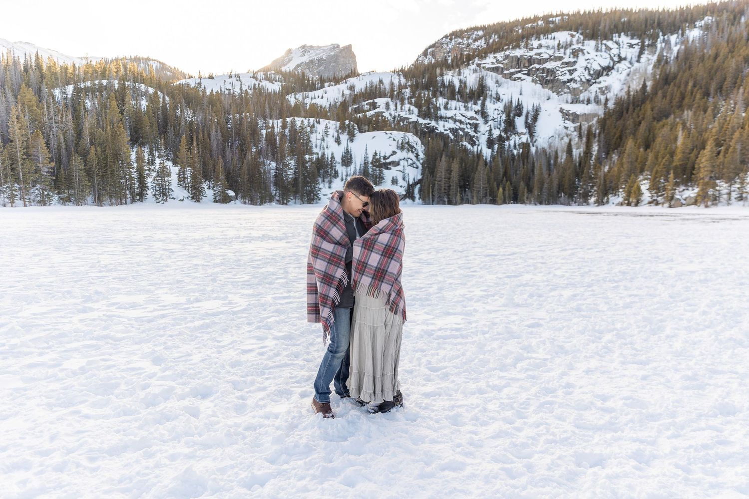 Snow-covered winter landscape with evergreen forest creates serene mountain setting.