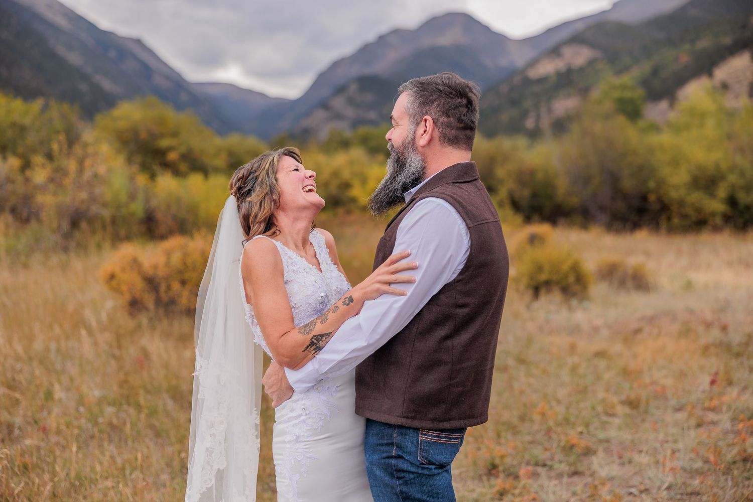 A couple dances and celebrates in a scenic mountain valley with autumn foliage and dramatic cloudy skies.