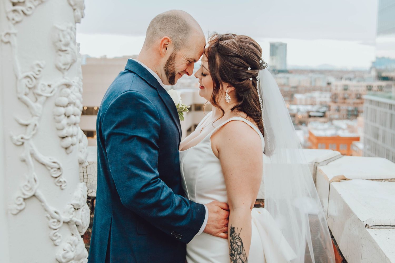 A bride and groom share an intimate moment during their wedding ceremony in an elegant white venue.