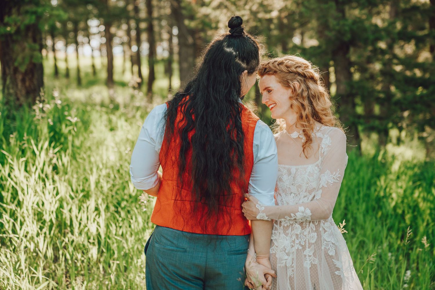 Two people in contrasting outfits walk together through a lush green meadow on a sunny summer day.