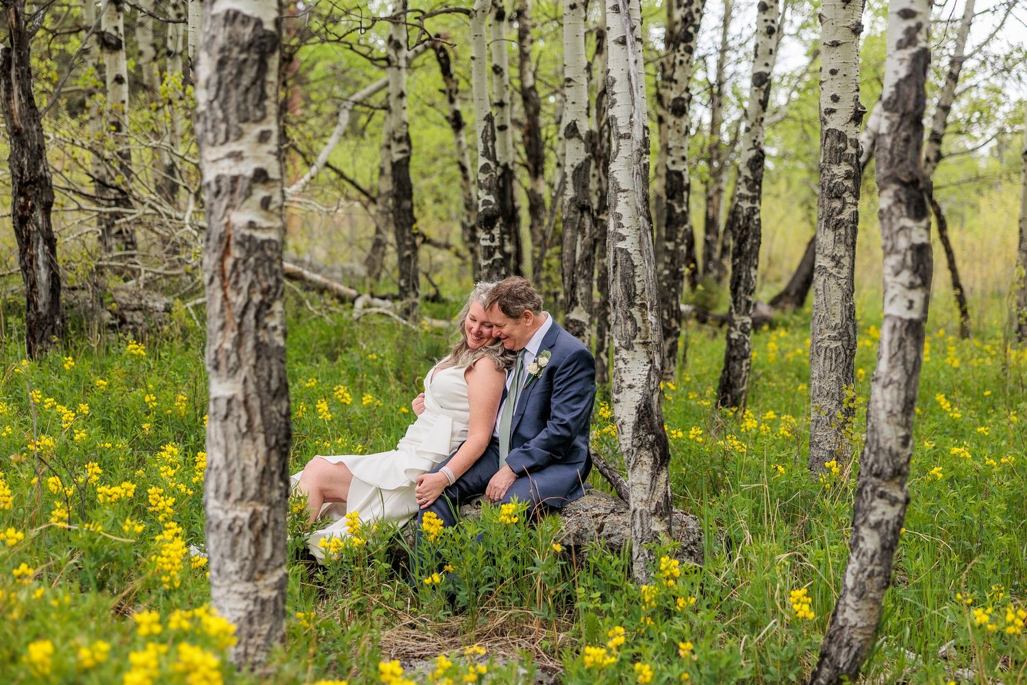 A romantic moment captured in a birch forest with yellow wildflowers blooming.
