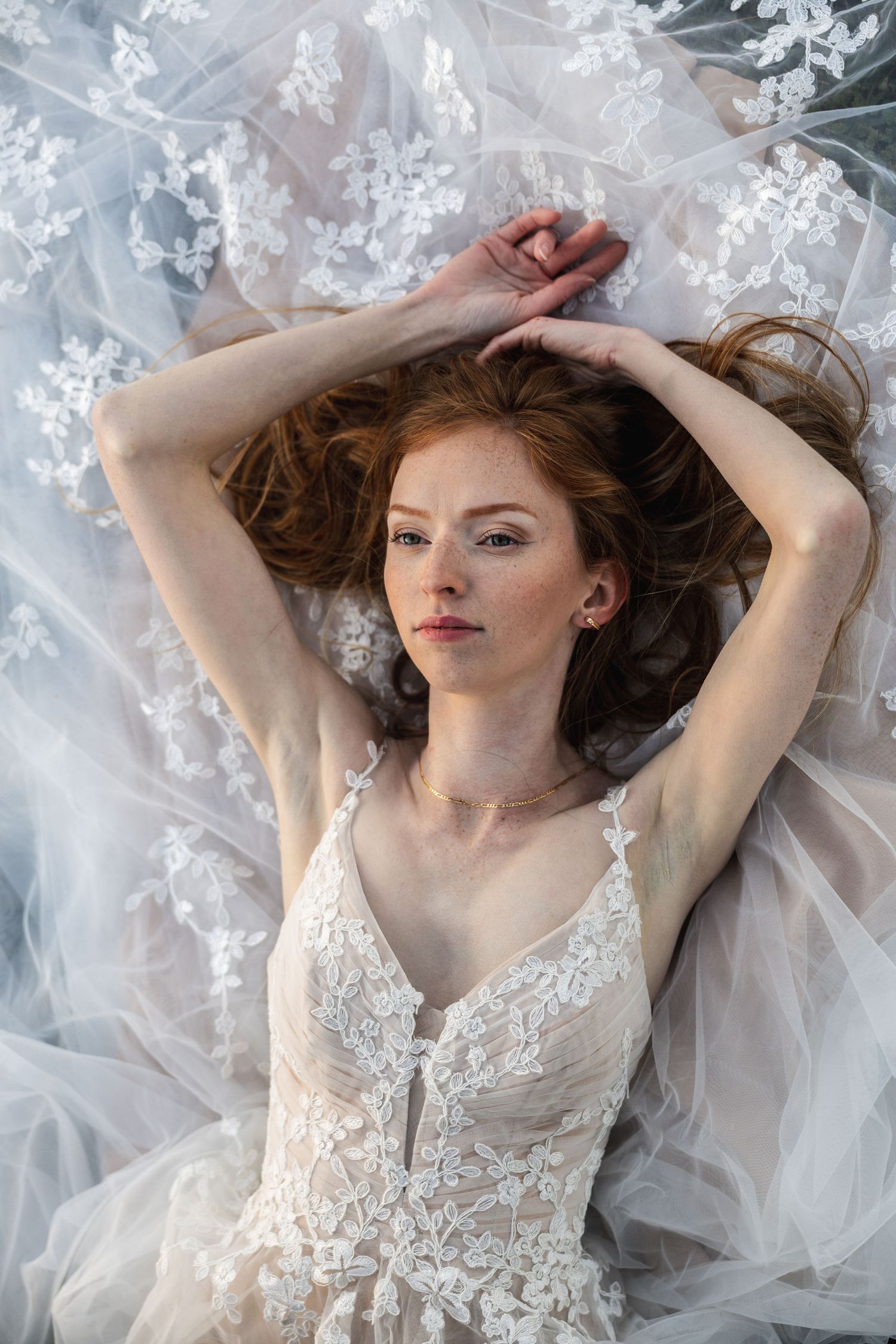 Ethereal bridal portrait featuring delicate lace dress and flowing veil.