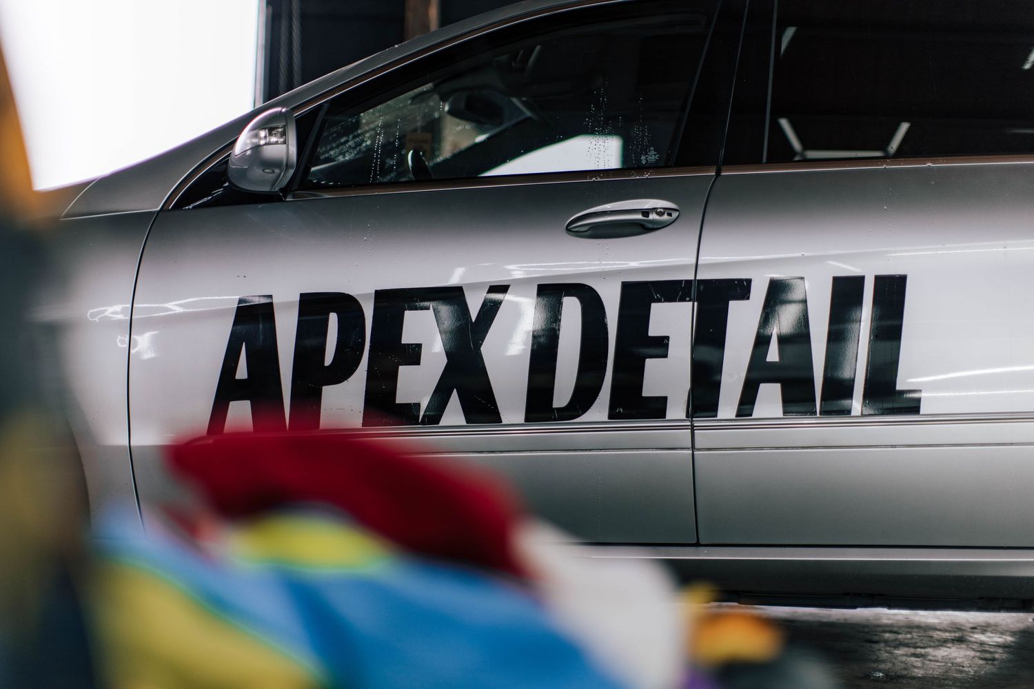 Professional car detailing service showing various vehicles being cleaned and polished to a high shine.