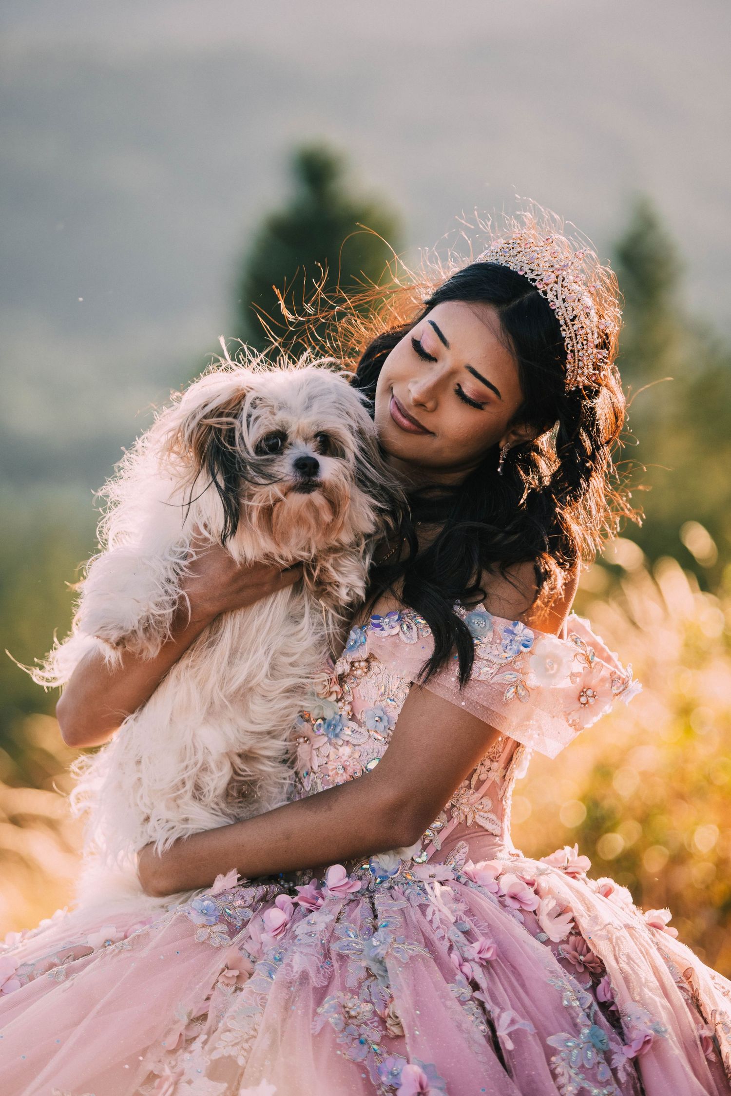A joyful moment captured between a person in a pink floral dress and their small fluffy dog at golden hour.