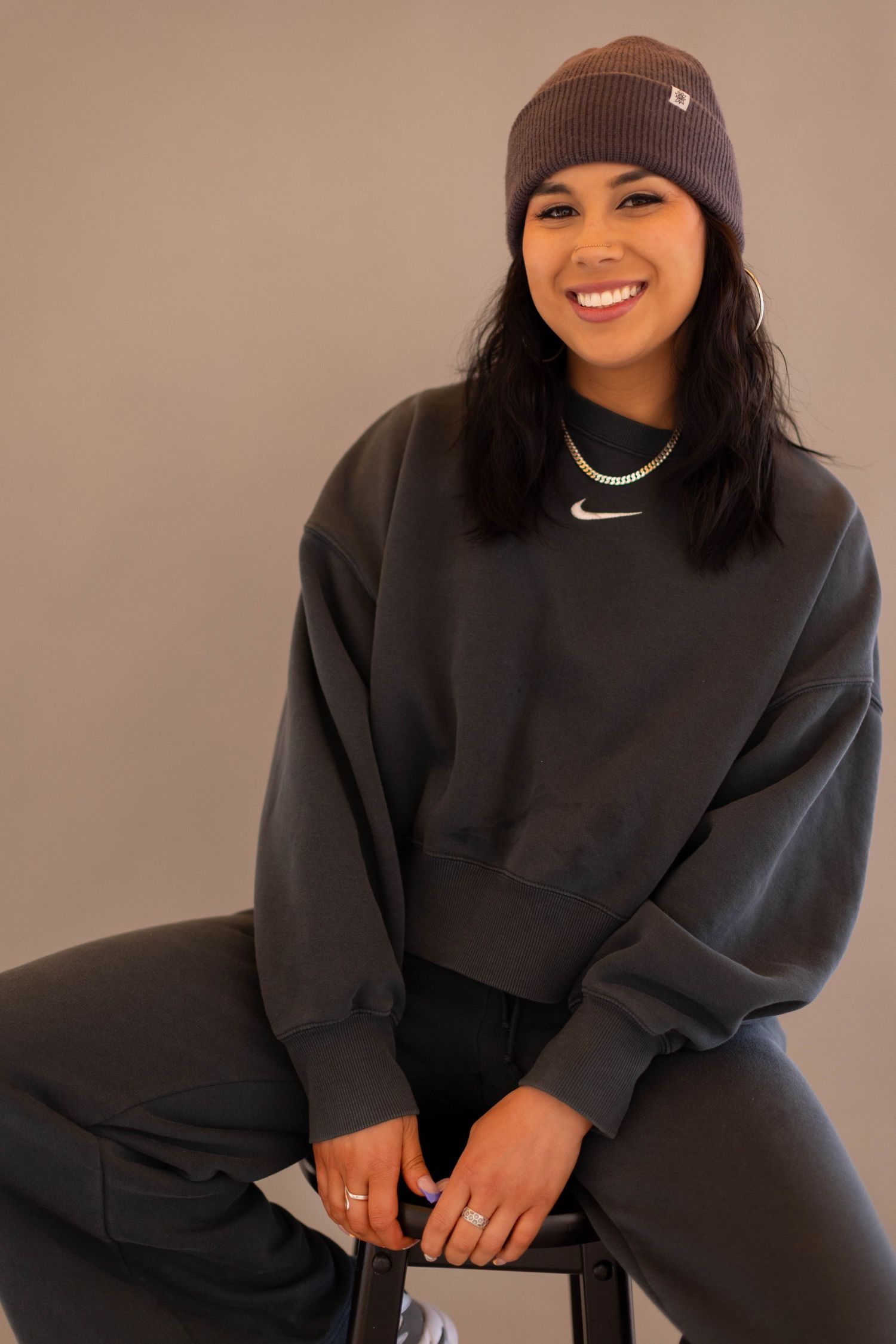 A series of photos showing someone wearing a brown beanie and black sweater posing casually against a neutral background.