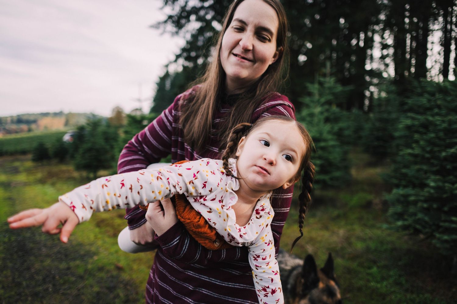 Playful couple poses together in a forest setting during golden hour with evergreen trees in background.