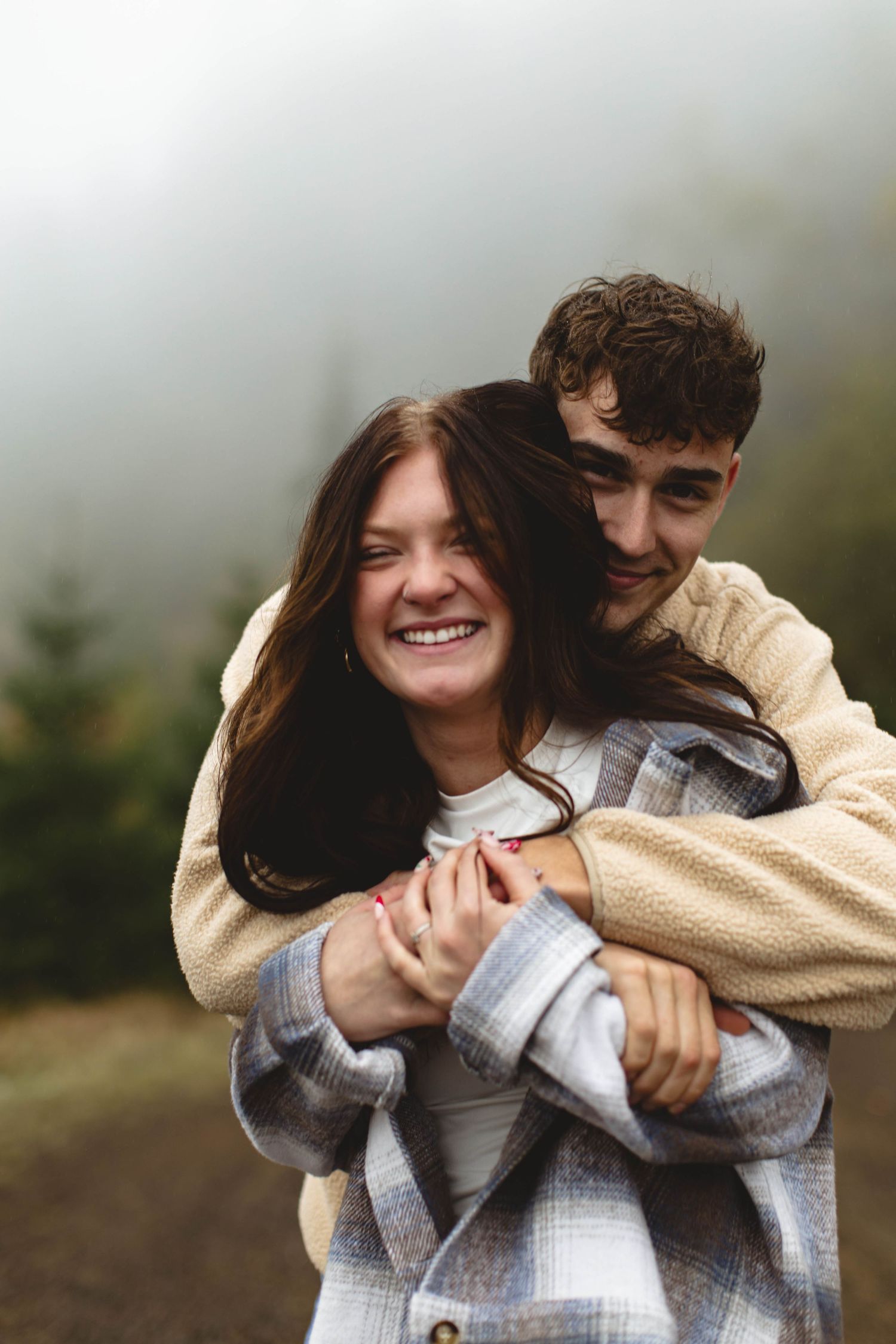 A couple in casual sweaters embrace and laugh together in a playful sequence of outdoor photos.