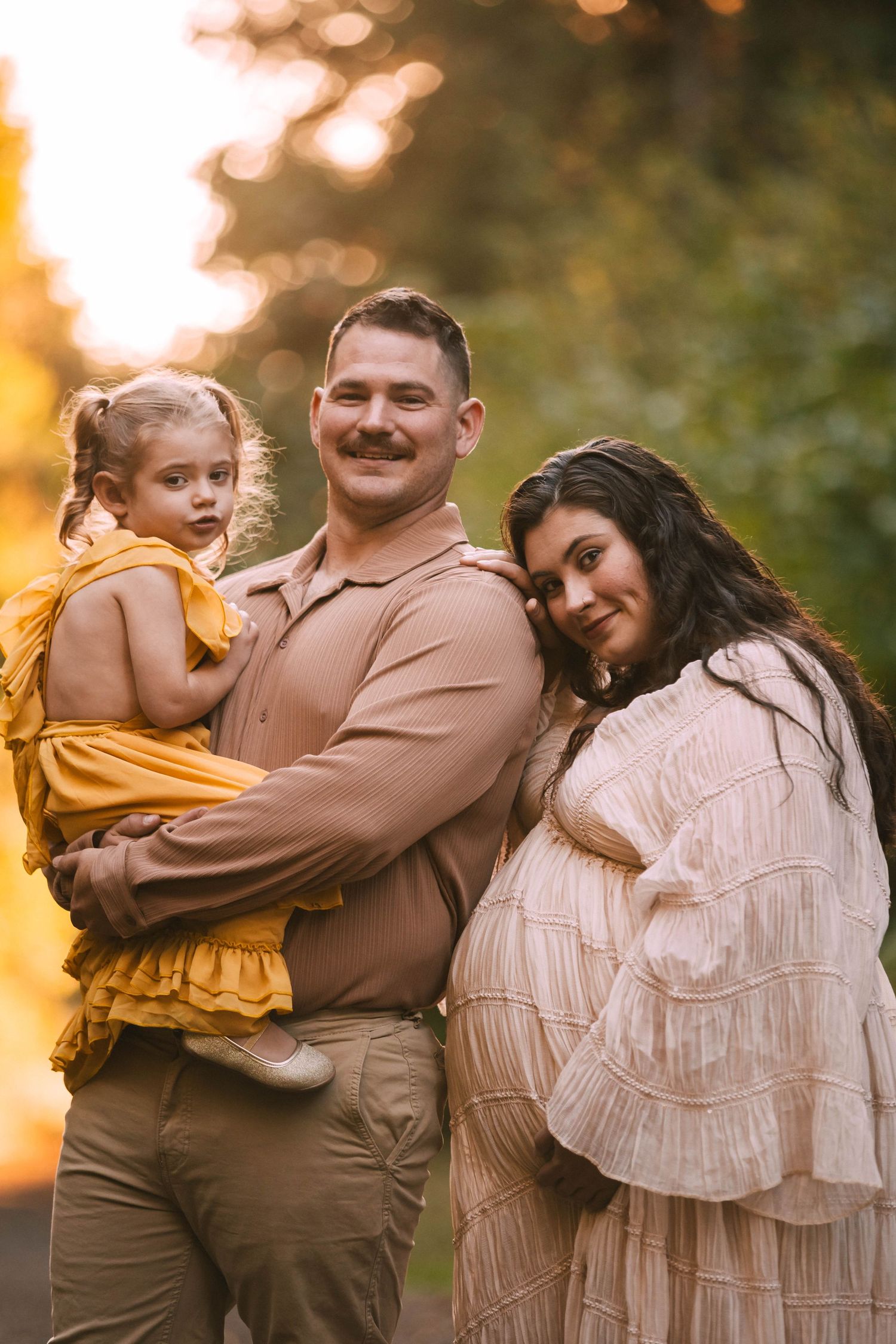 A family shares tender moments together outdoors during sunset in coordinated brown and yellow outfits.