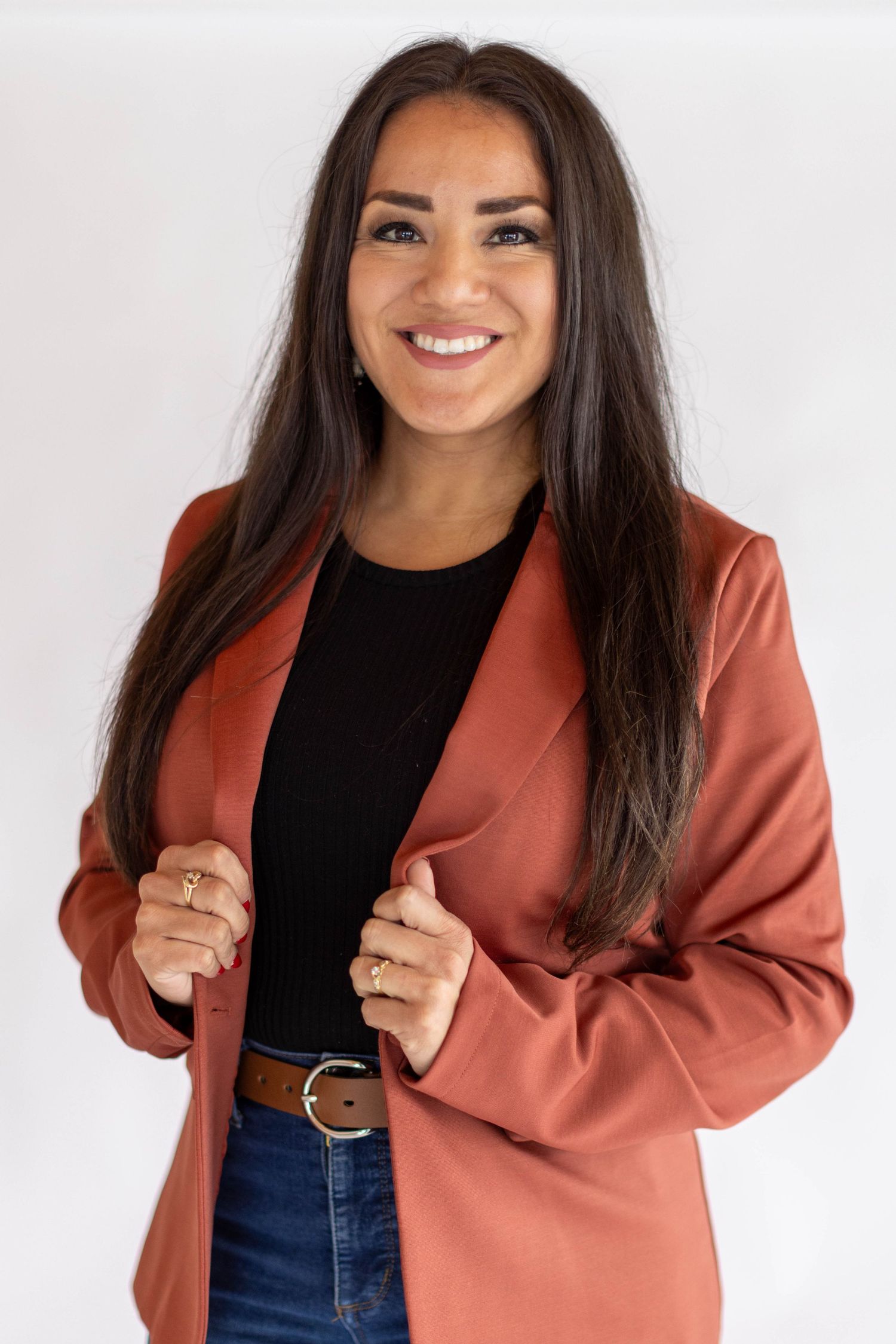Professional fashion model wearing black top and rust colored blazer poses in four different poses against white background.