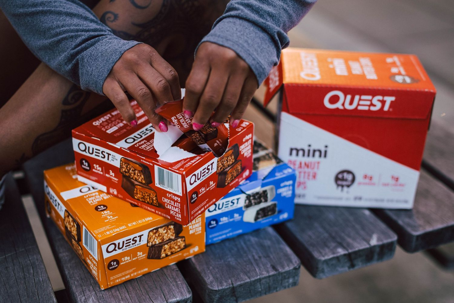 Various Quest protein bars and snacks arranged on dark surface.