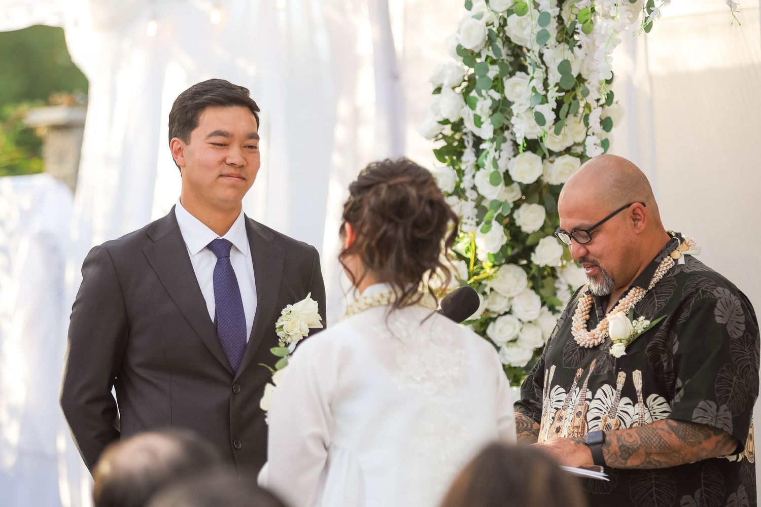 Wedding guests and newlyweds gather in an elegant reception space decorated with hanging floral arrangements.