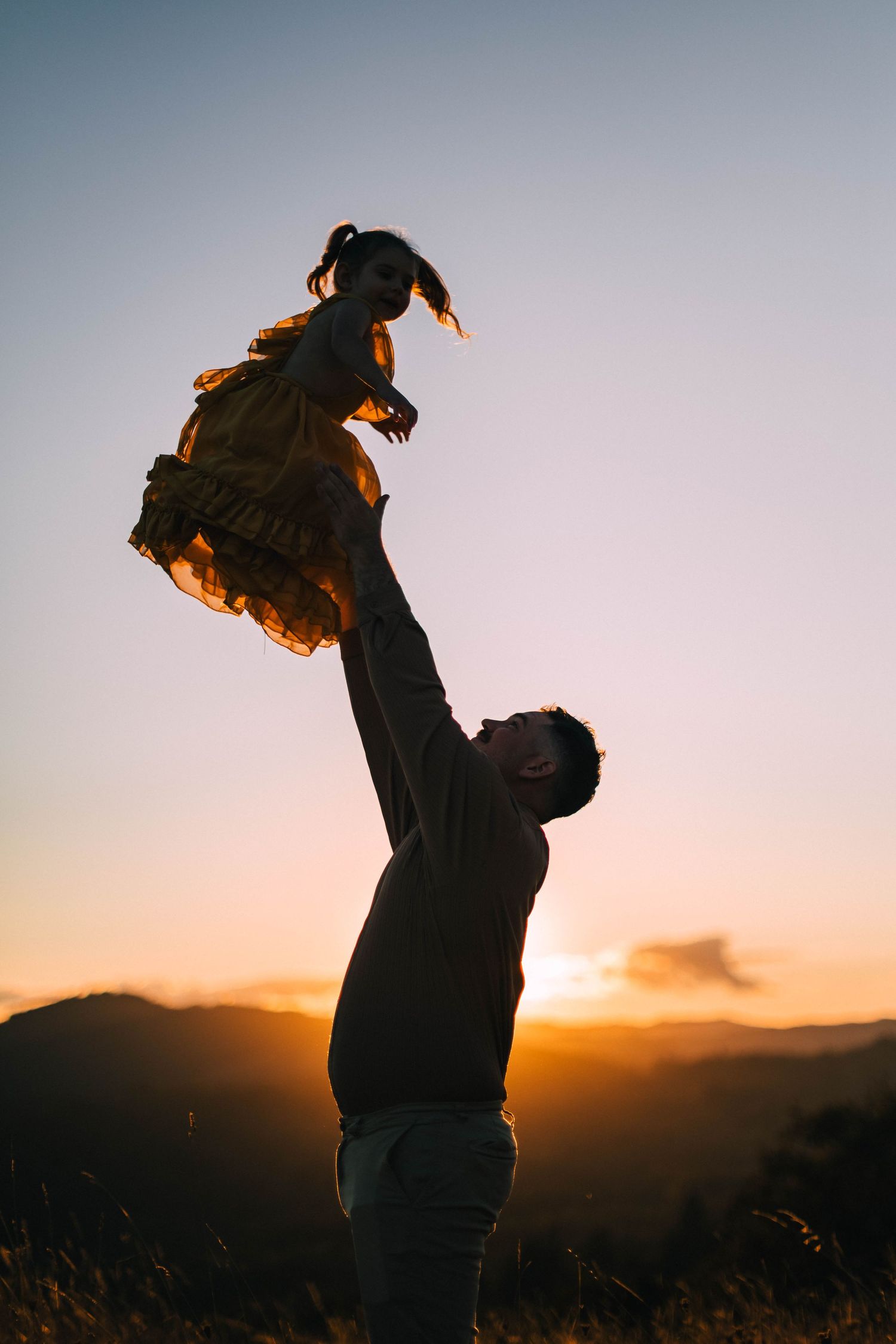 Silhouettes of a couple embracing against a sunset mountain backdrop.