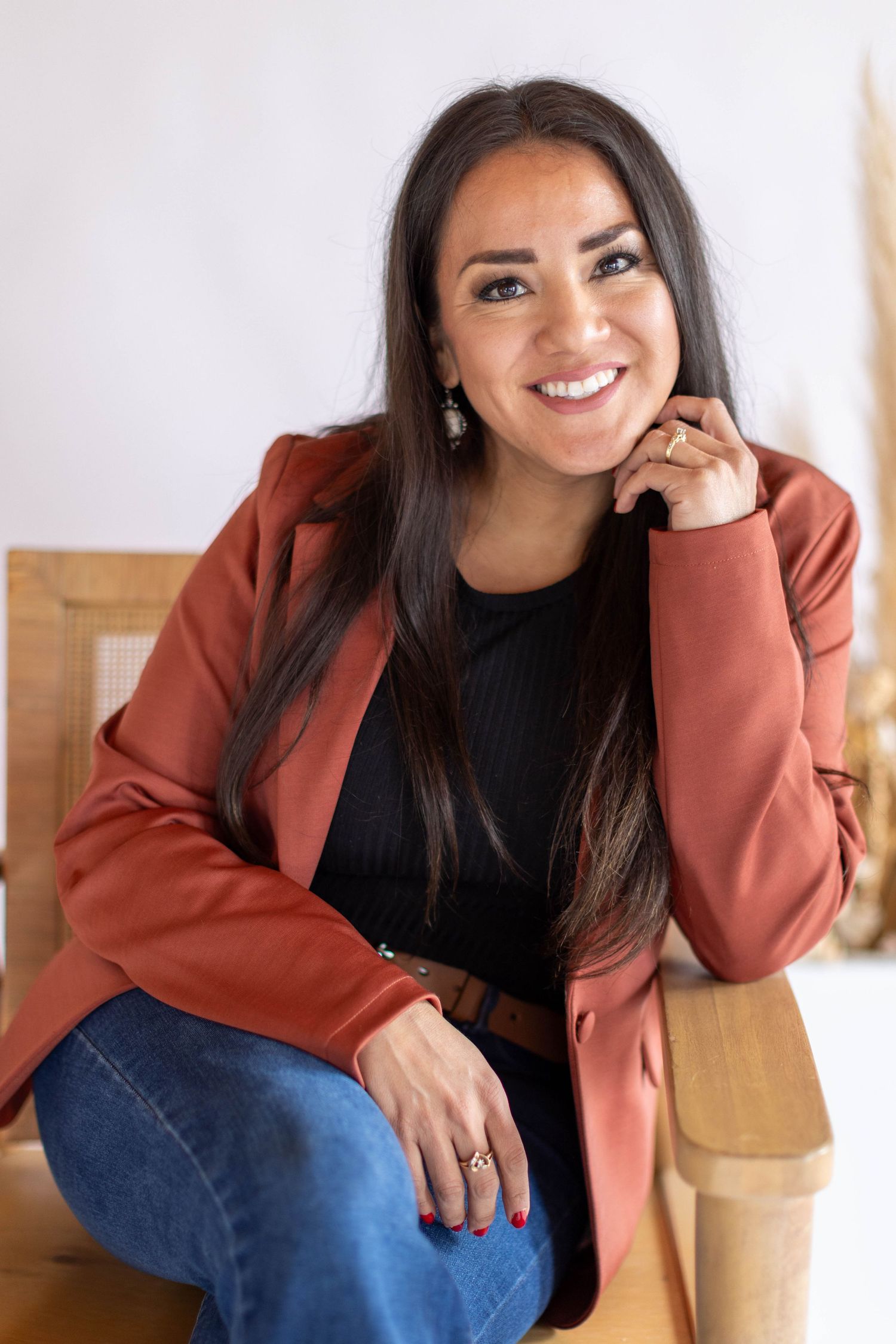 Person in casual attire sits relaxed on wooden chair showing various expressions in bright studio setting.