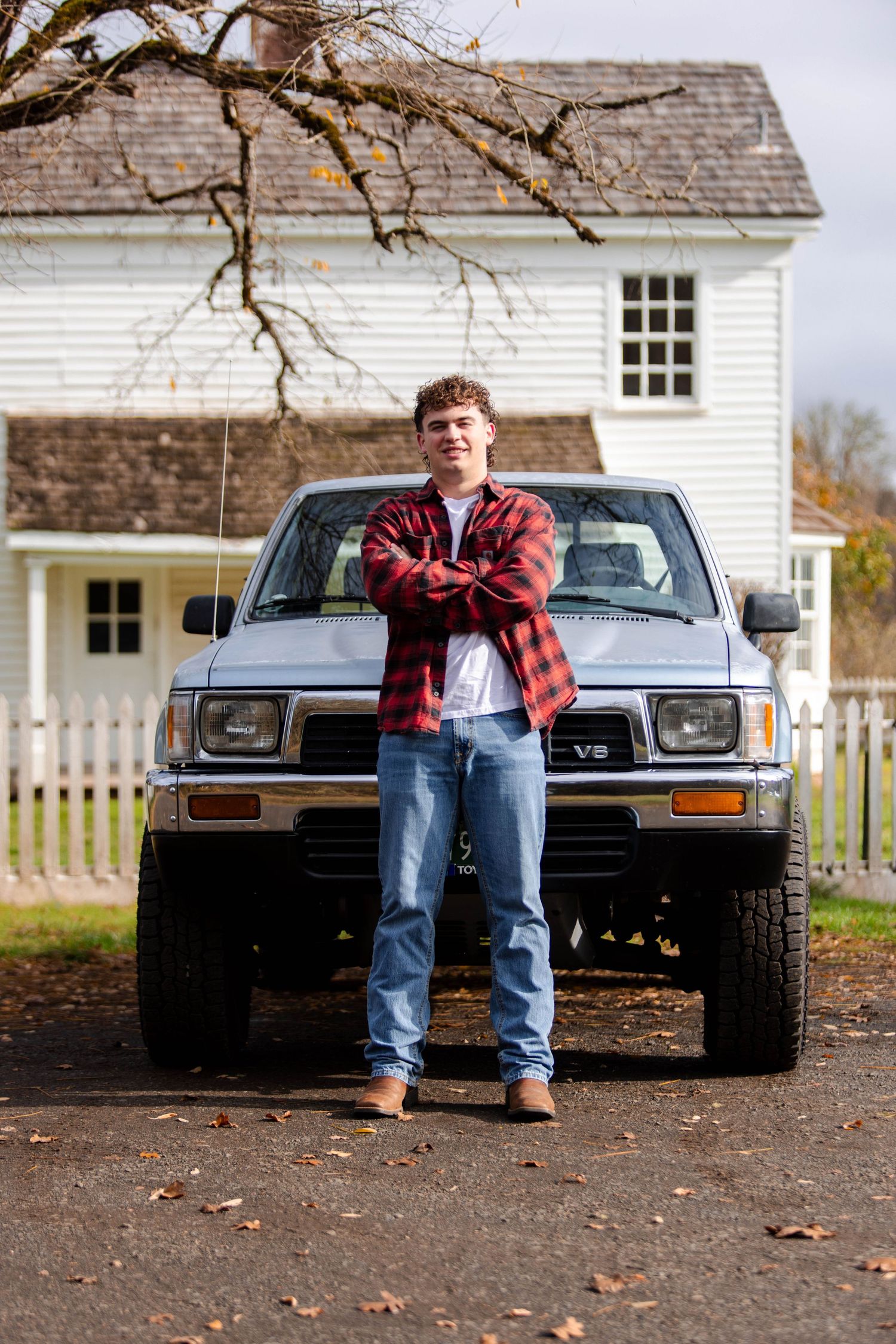 Four sequential photos showing someone sitting on the front bumper of a black vintage car parked in front of a white building.