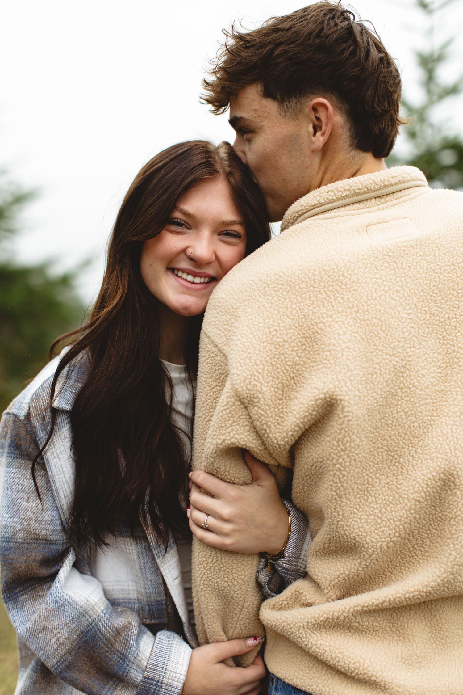 A couple embraces outdoors wearing cozy sweaters while sharing intimate laughs in a series of candid moments.