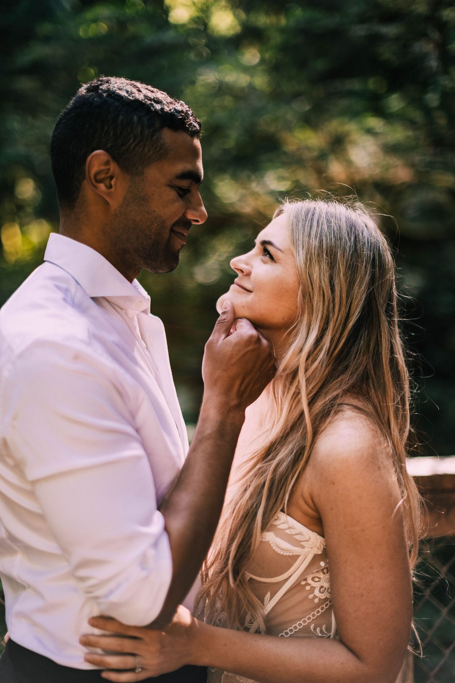 A romantic couple shares intimate moments and laughter during an outdoor photo session in natural lighting.