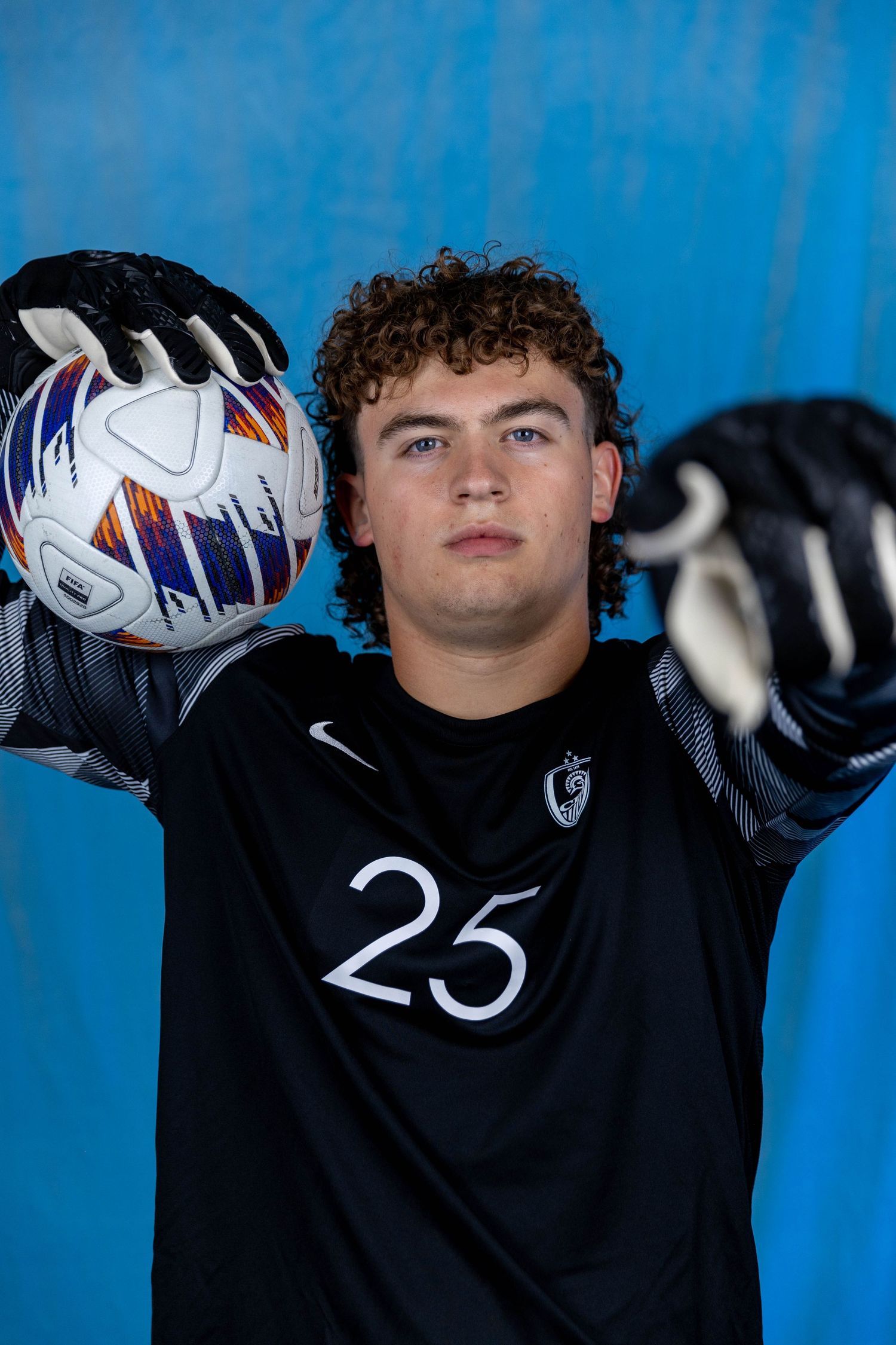 Soccer player in black jersey holds up ball against blue background in dynamic action pose sequence.