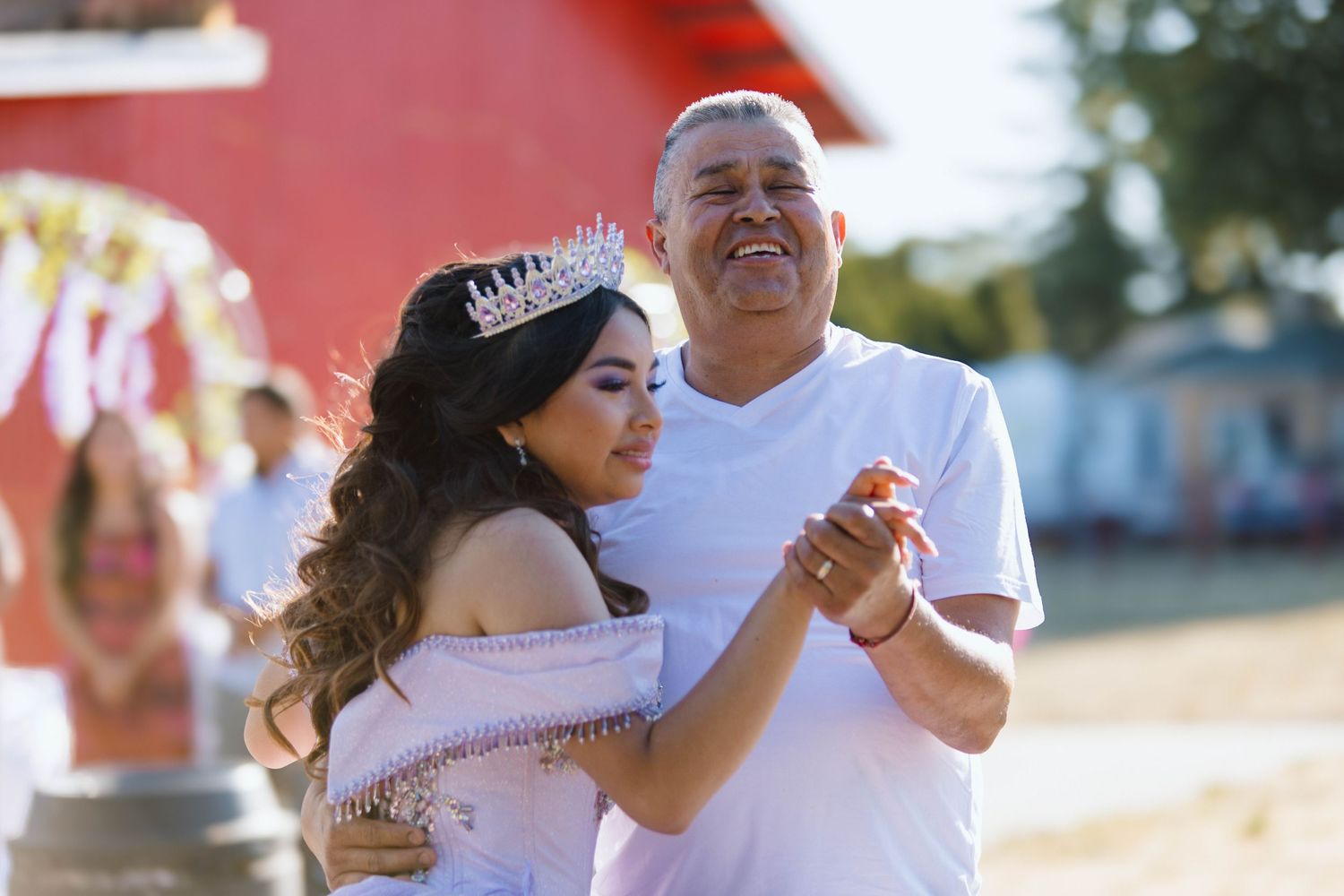 A couple shares a romantic dance on a sunny beach during a wedding celebration.