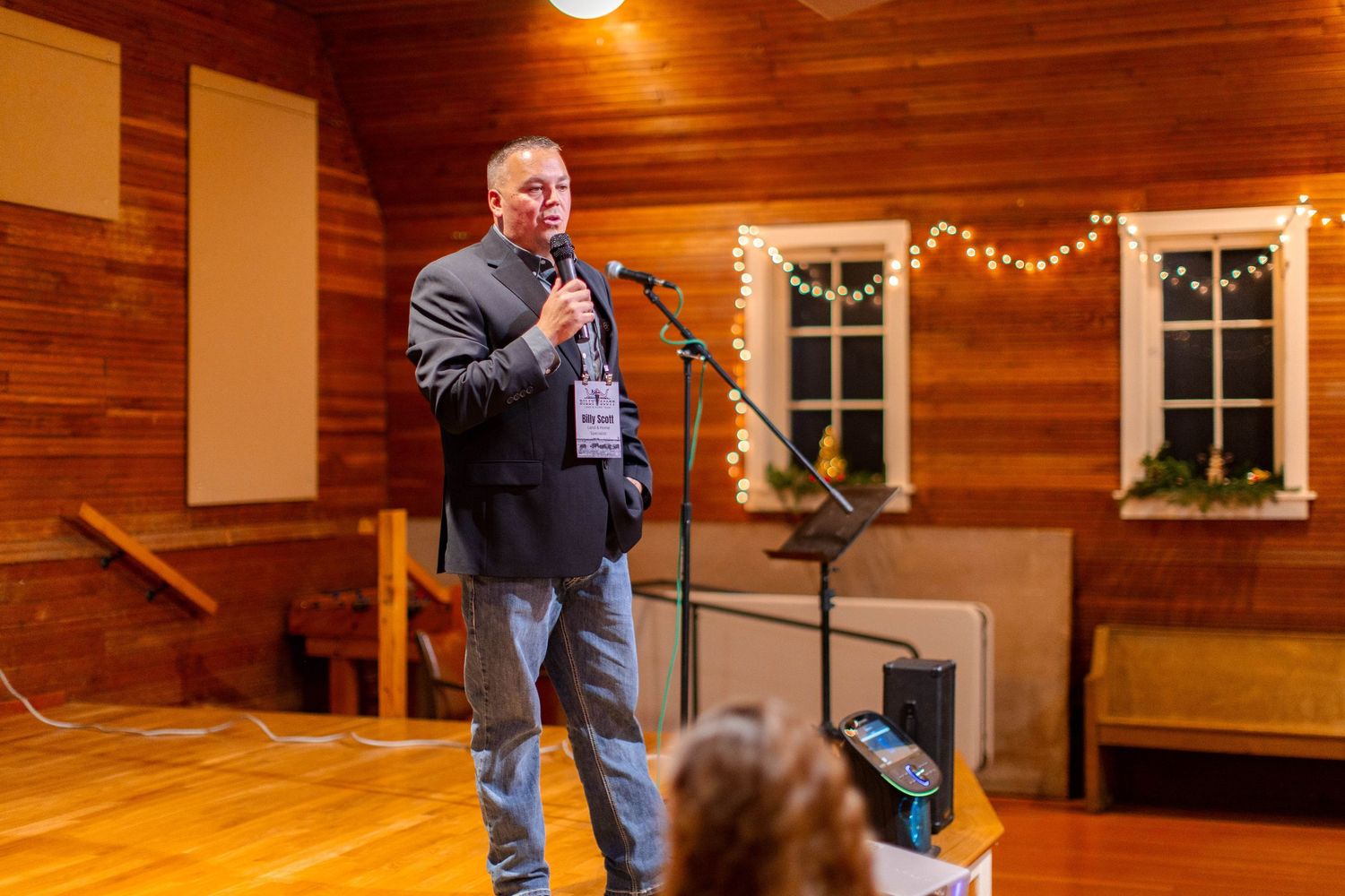 People gathered in a rustic wood-paneled room with warm lighting and windows visible in the background.