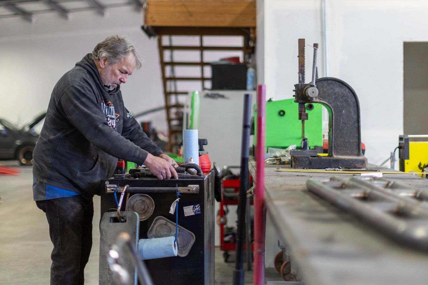 A person works at a machining station in an industrial workshop setting, operating precision equipment.