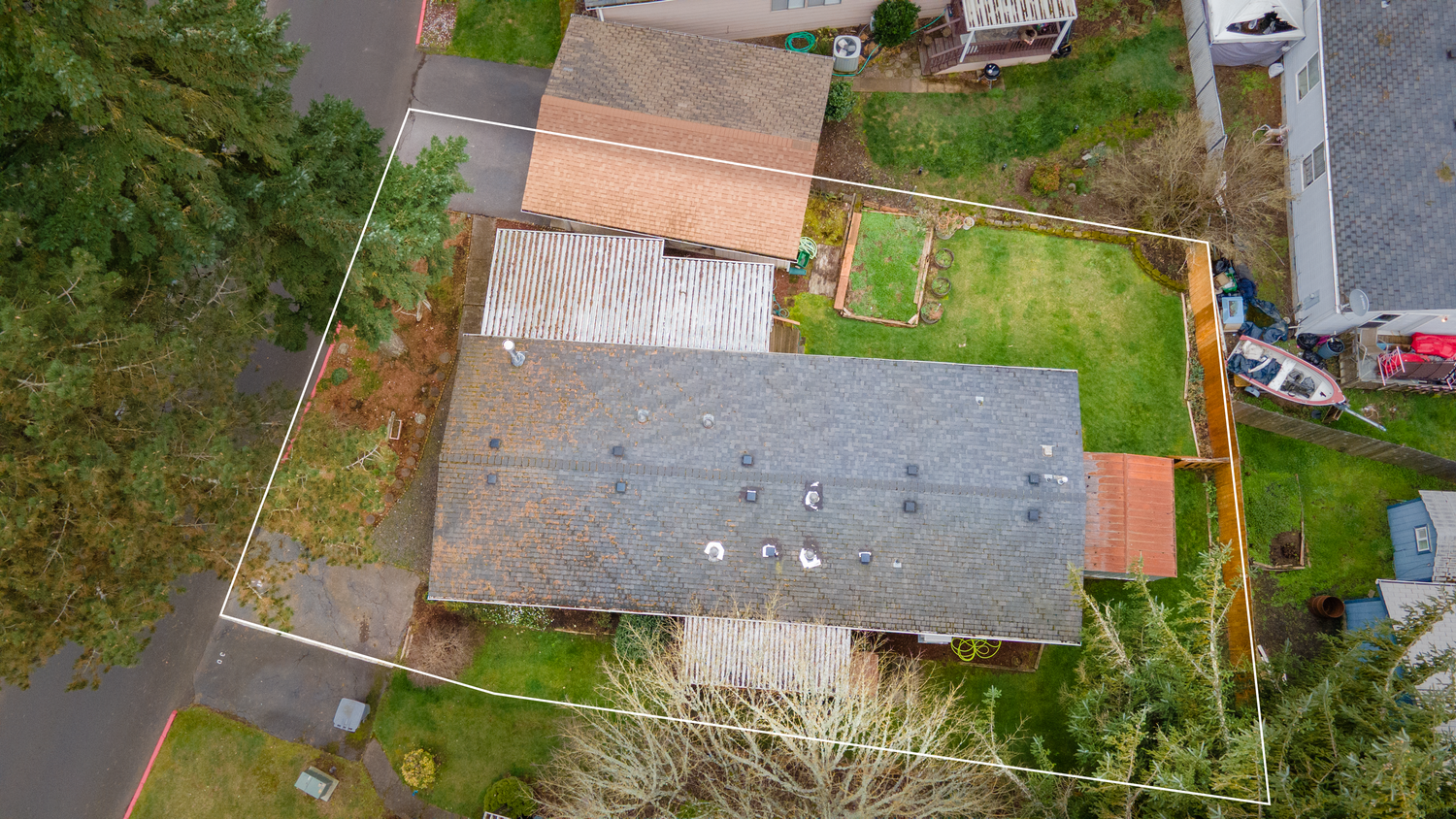 Aerial drone footage shows residential rooftops and green yards in a suburban neighborhood during autumn.