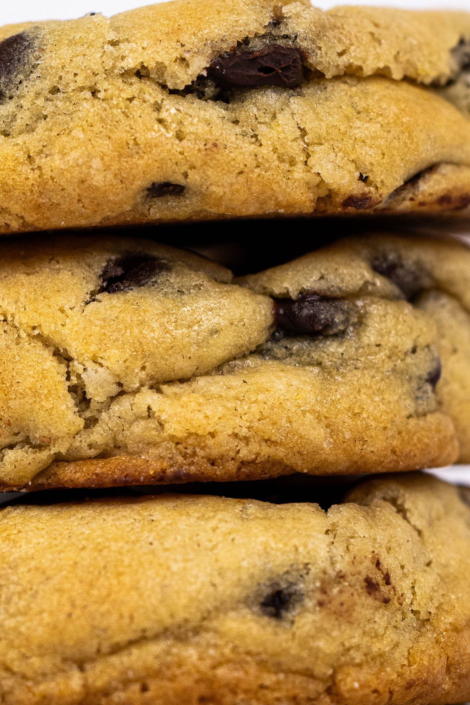 Close-up view of freshly baked chocolate chip cookies stacked together showing golden brown edges and melty chocolate chips.